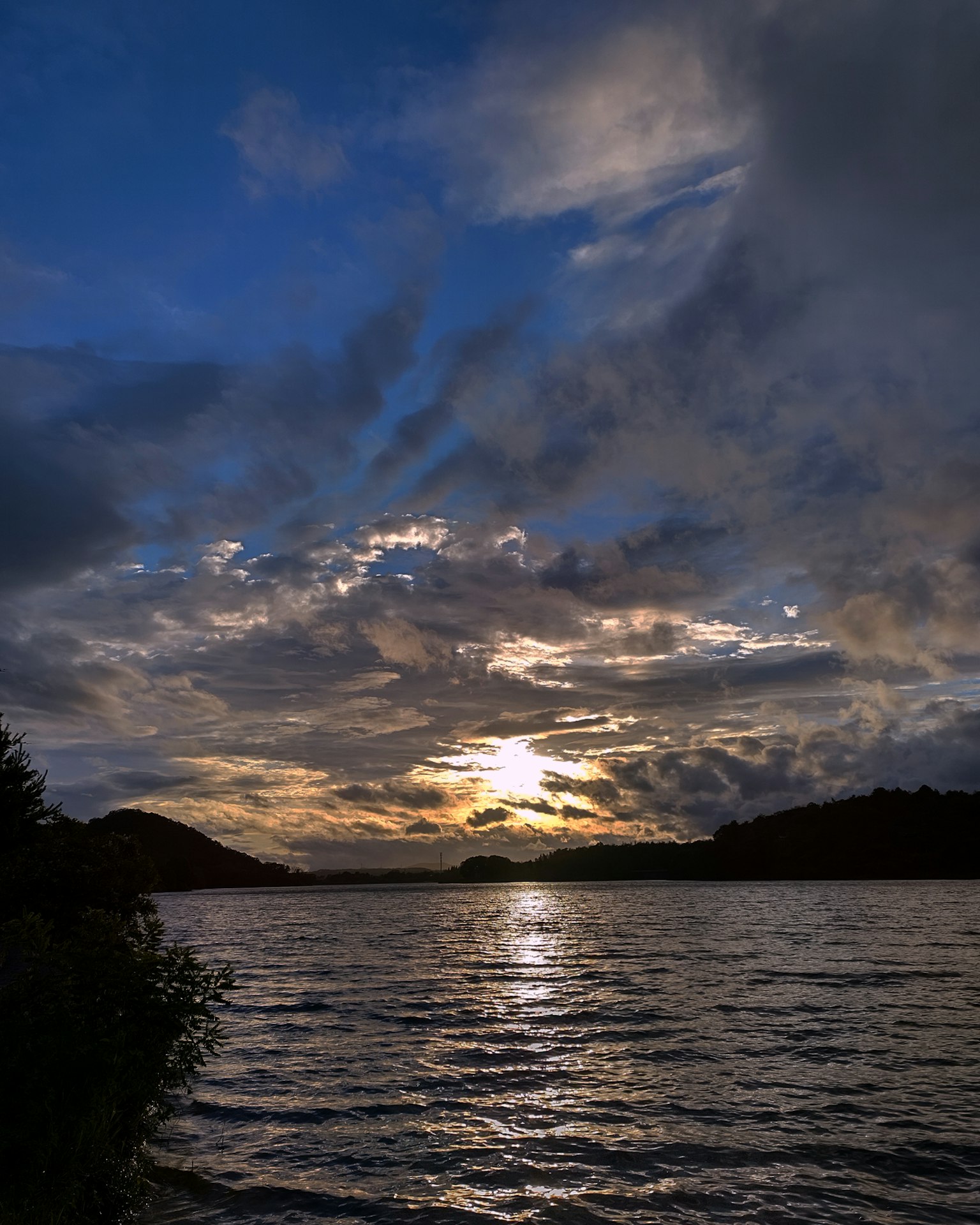 Paisaje con atardecer reflejado en el agua y cielo nublado