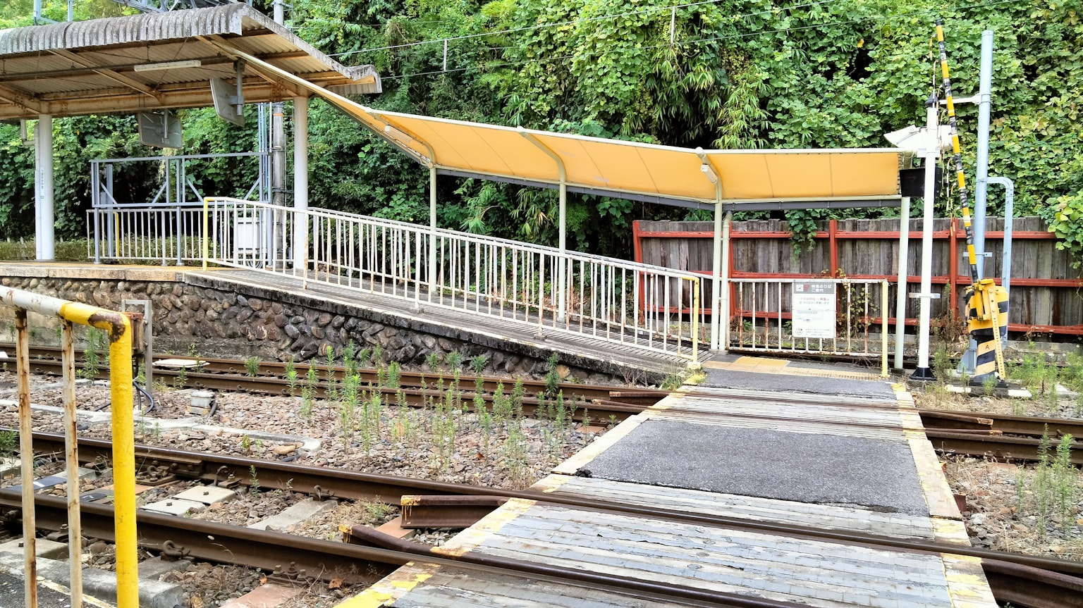 Vista de una plataforma de tren con un toldo amarillo y rieles