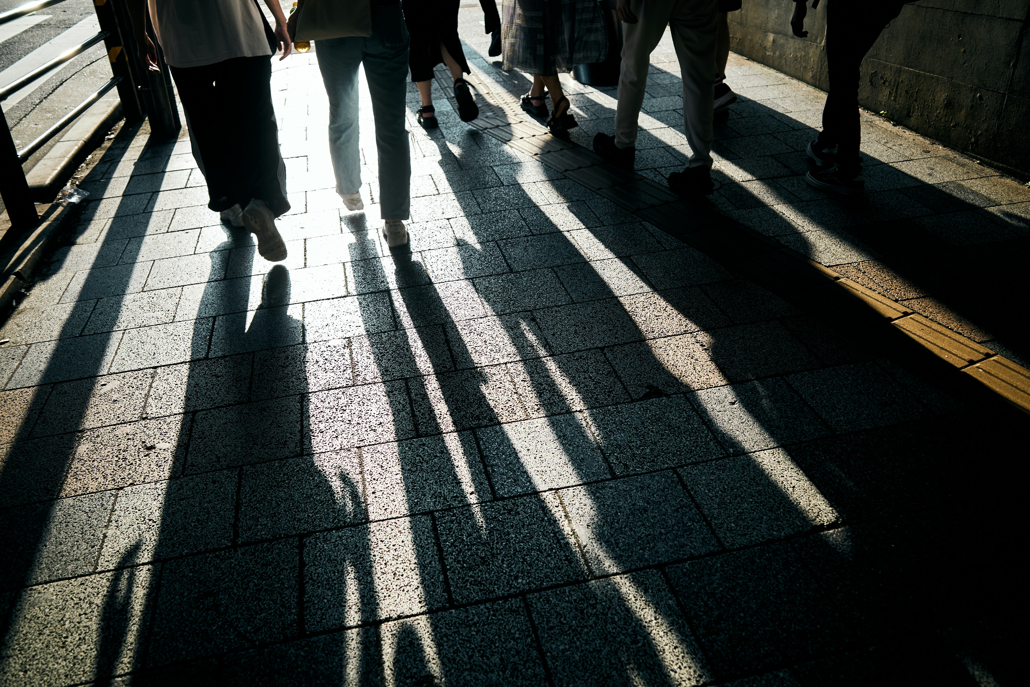 people walking on a sunlit city sidewalk