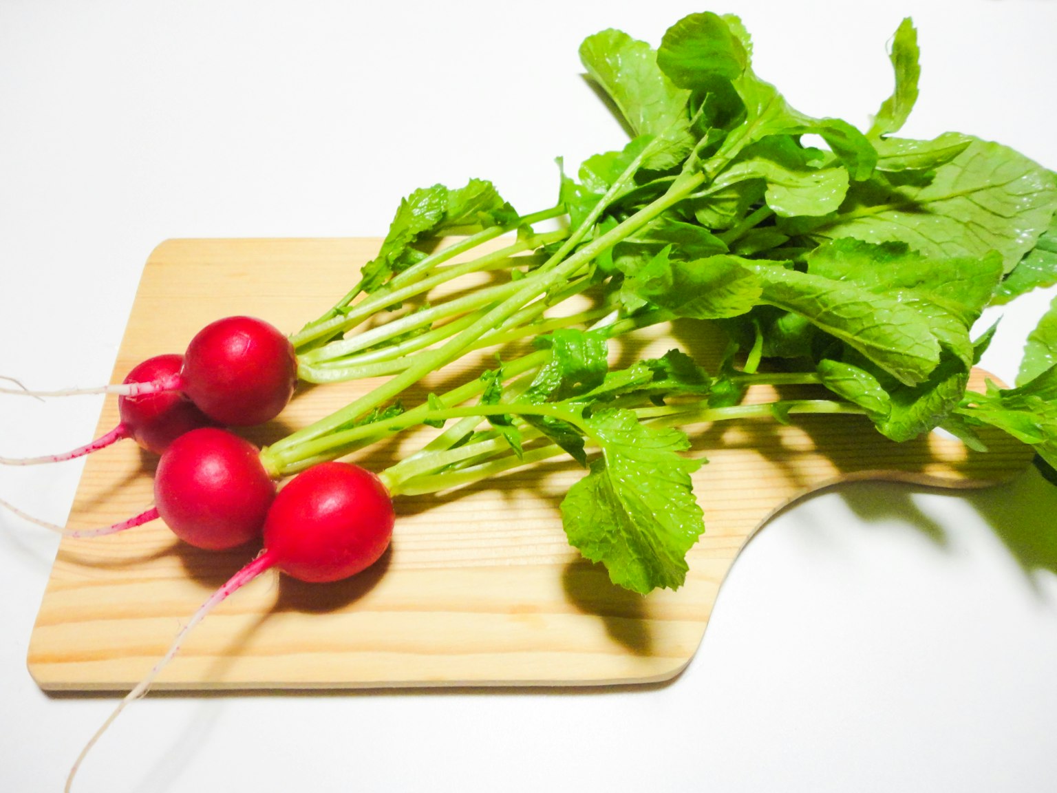 Rábanos rojos frescos con hojas verdes sobre una tabla de madera