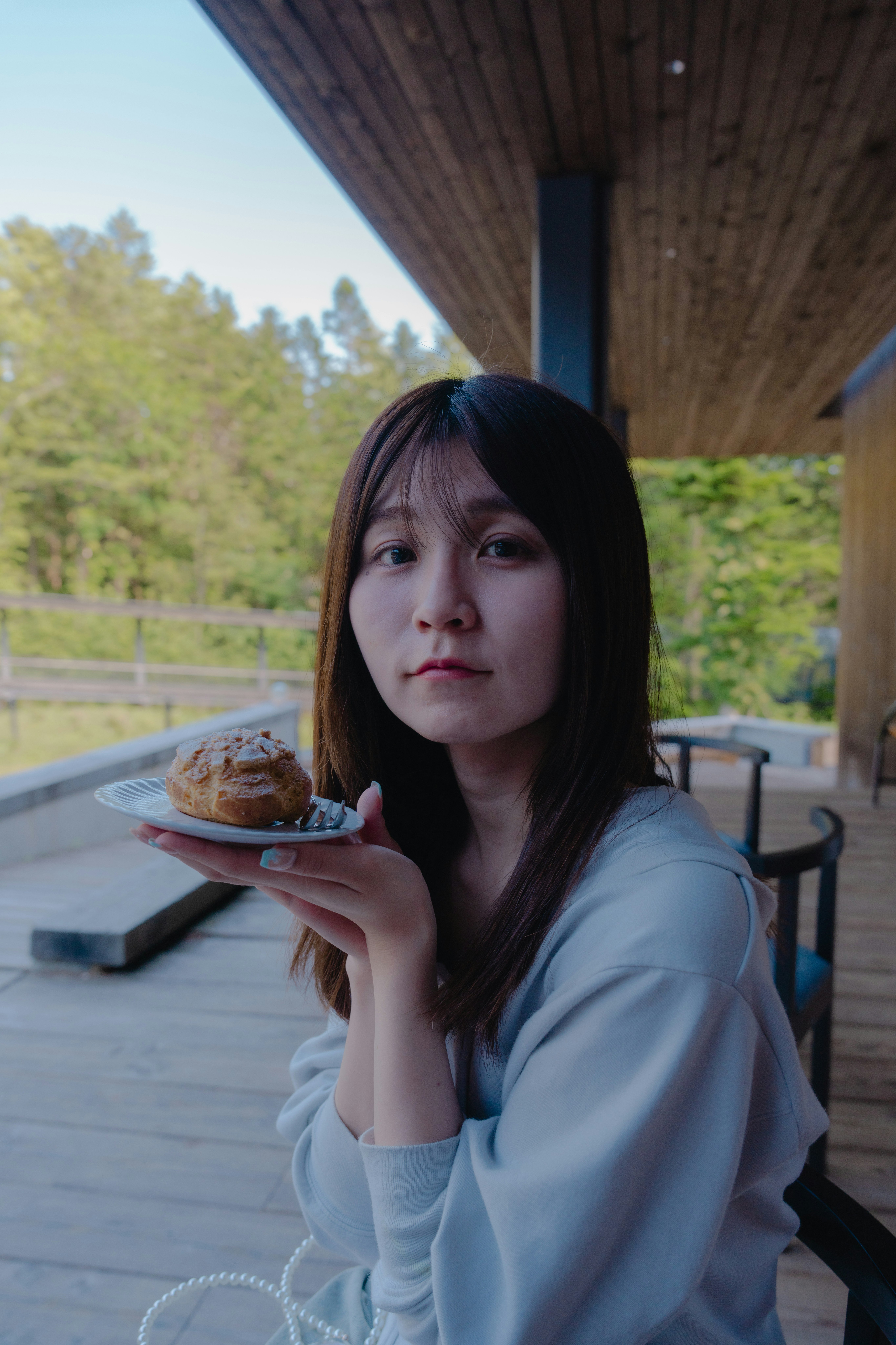 木のベランダで手に持ったパンを見つめる女性