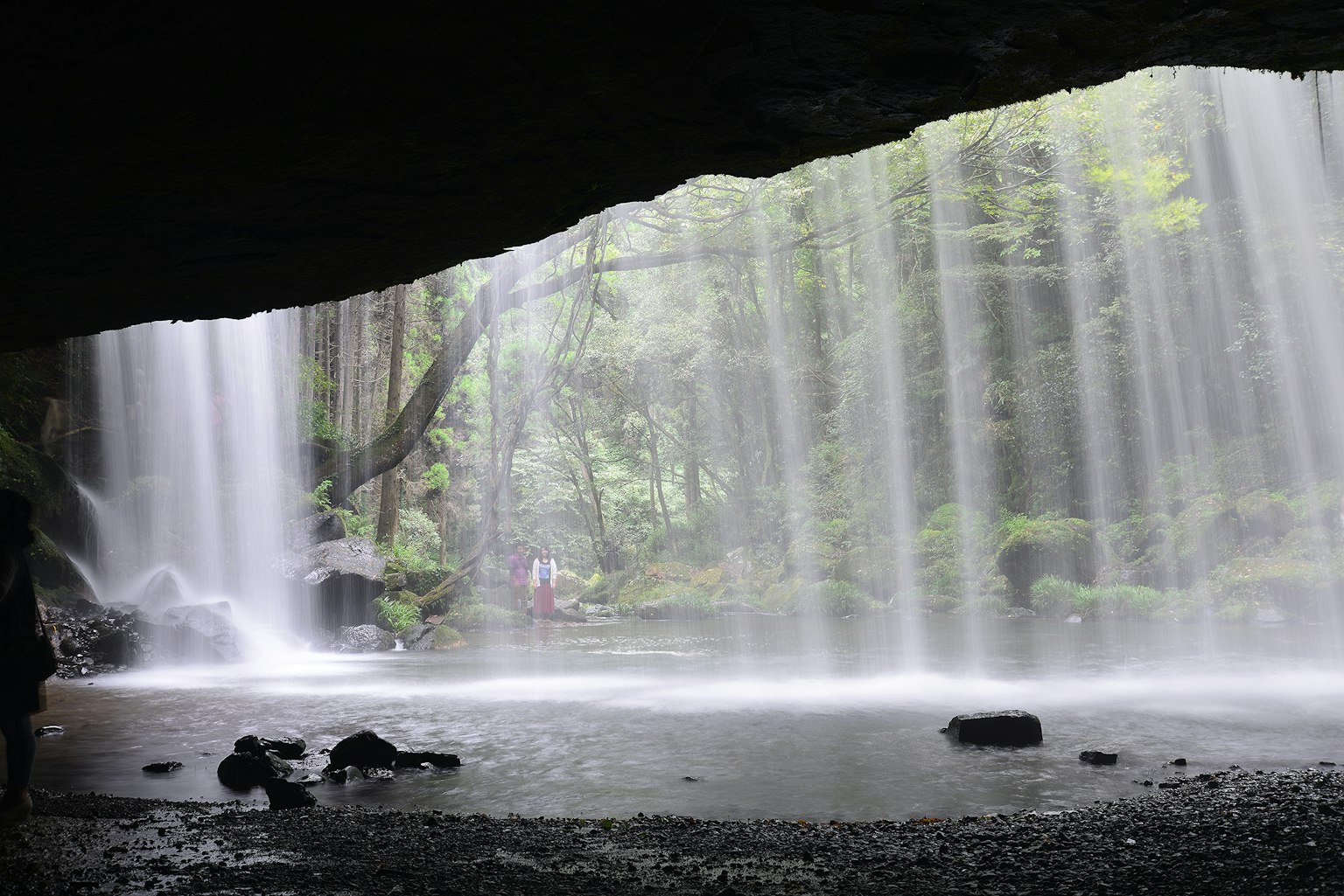 Pemandangan hijau subur dan tirai air dari belakang air terjun