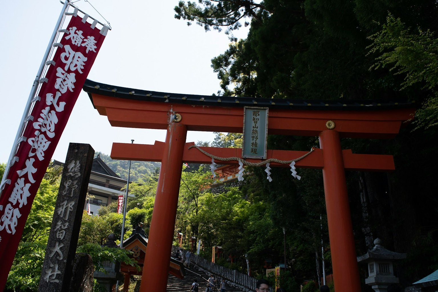 Cổng torii màu đỏ với cây cối xanh tươi tại lối vào đền