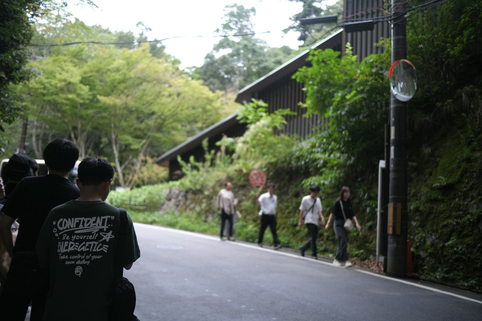 Group of people walking along a road surrounded by greenery
