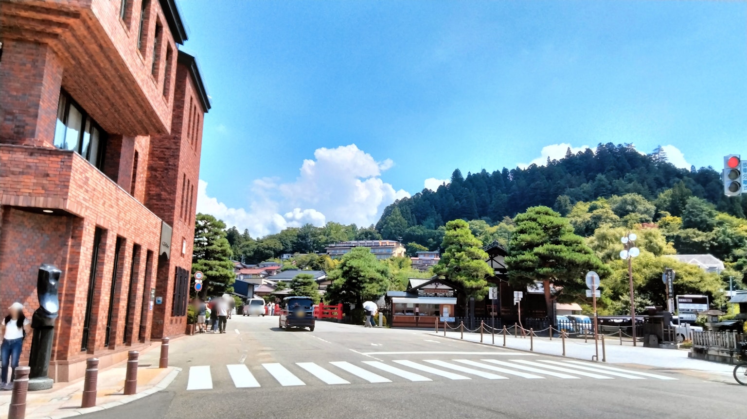 Urban landscape with brick building and crosswalk against a backdrop of hills and blue sky