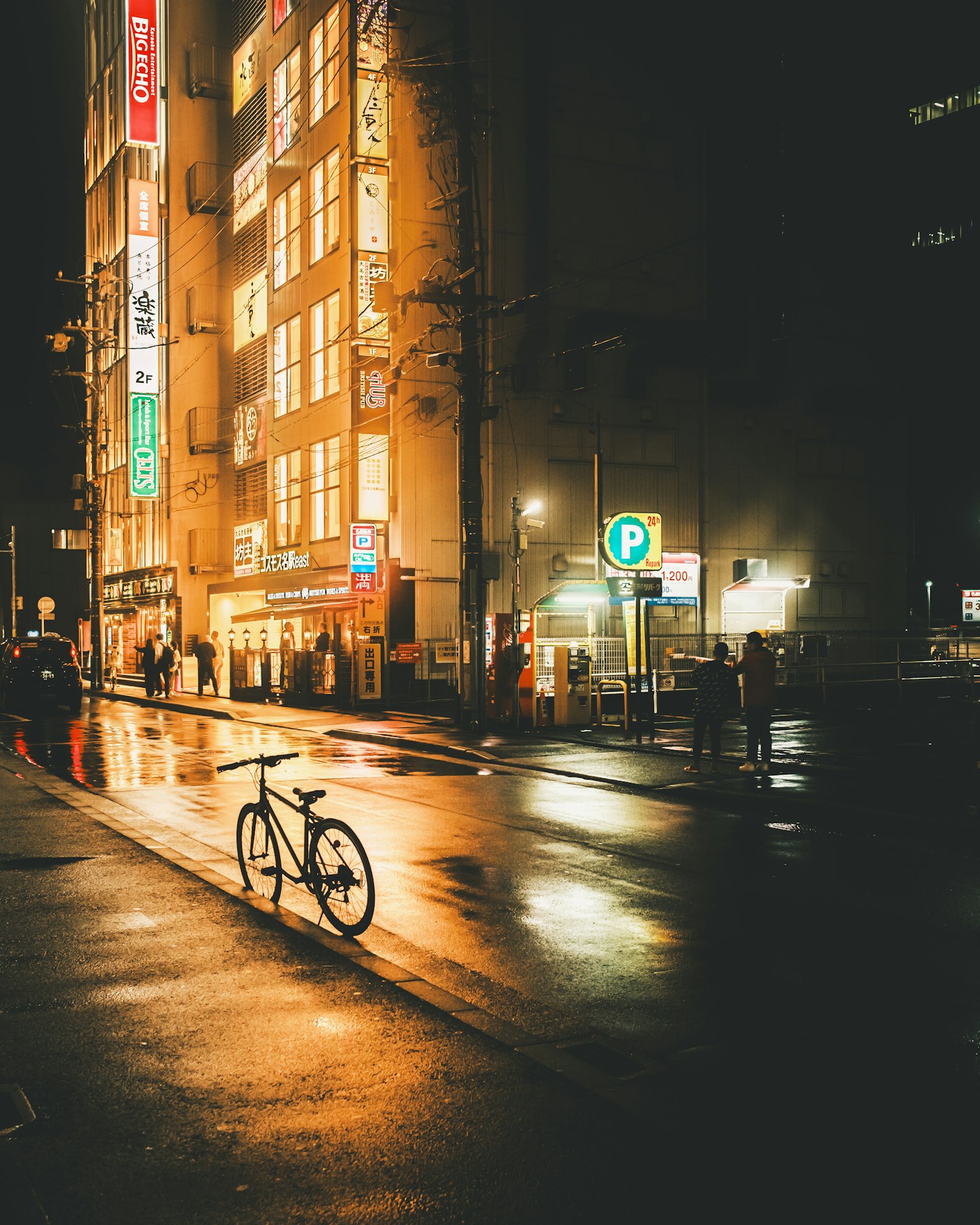 Bicicleta de pie en una calle mojada reflejando las luces de la ciudad por la noche