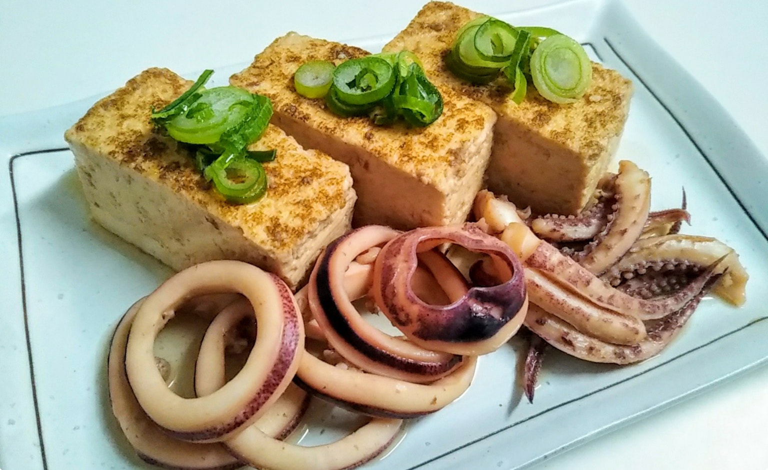 Tofu cubierto con cebollín servido con calamares