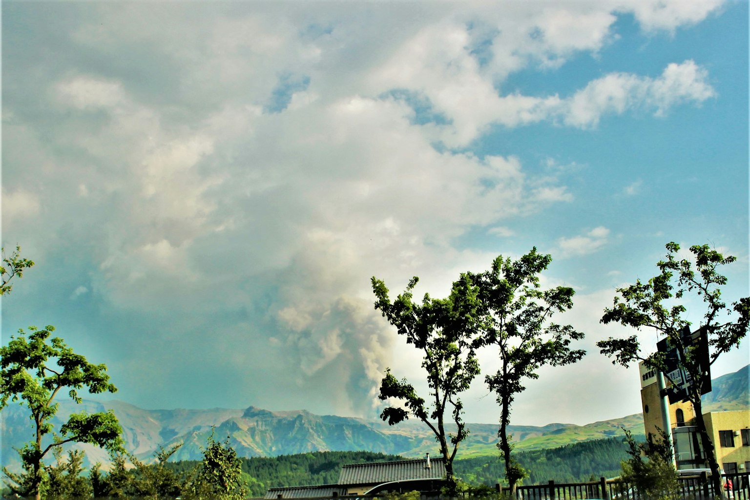 Gunung mengeluarkan asap dengan awan di langit biru