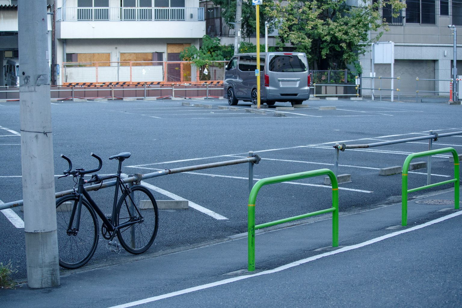 Una bicicleta aparcada en un estacionamiento vacío con barreras verdes