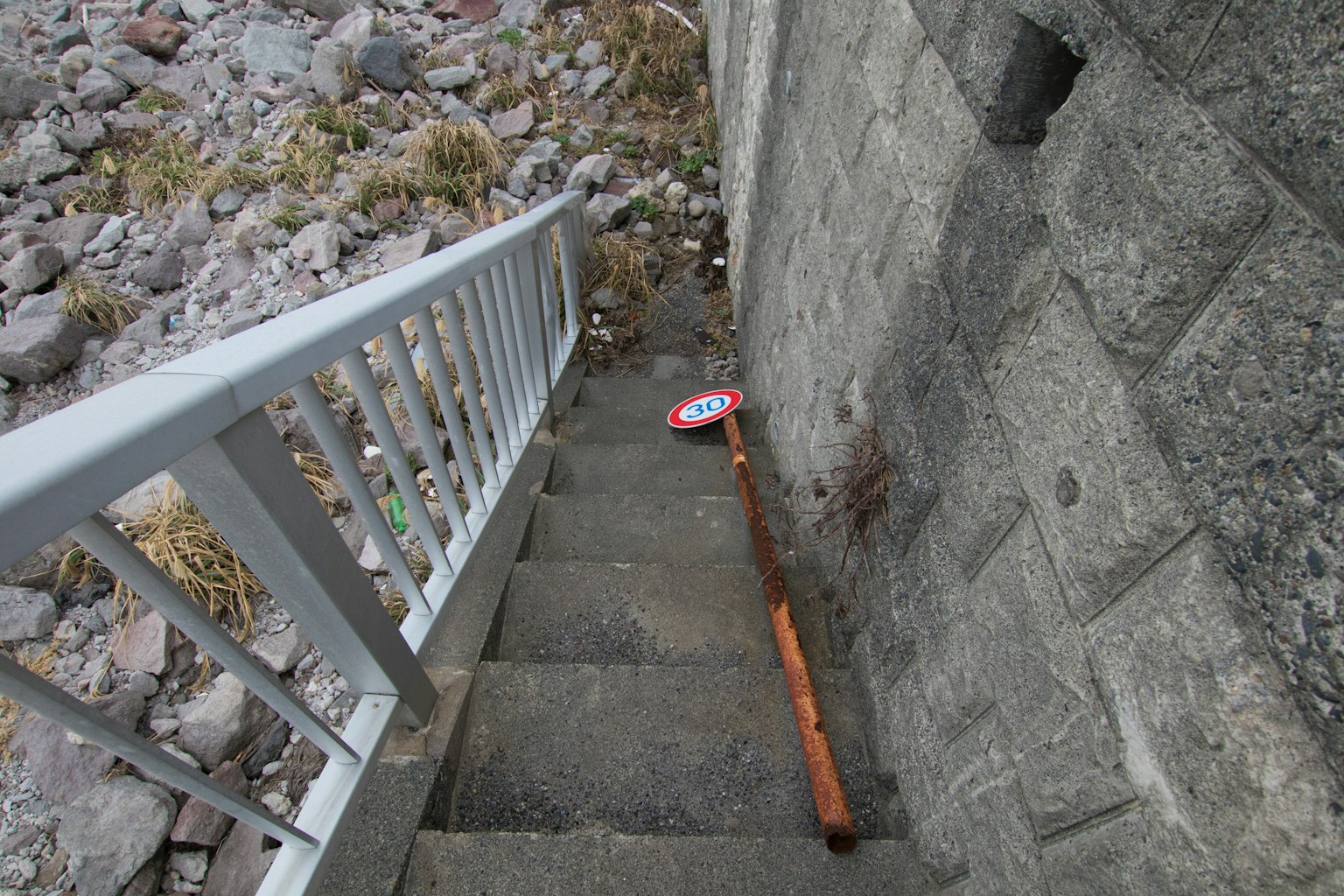 Photo showing a red sign and a wooden stick at the bottom of a staircase
