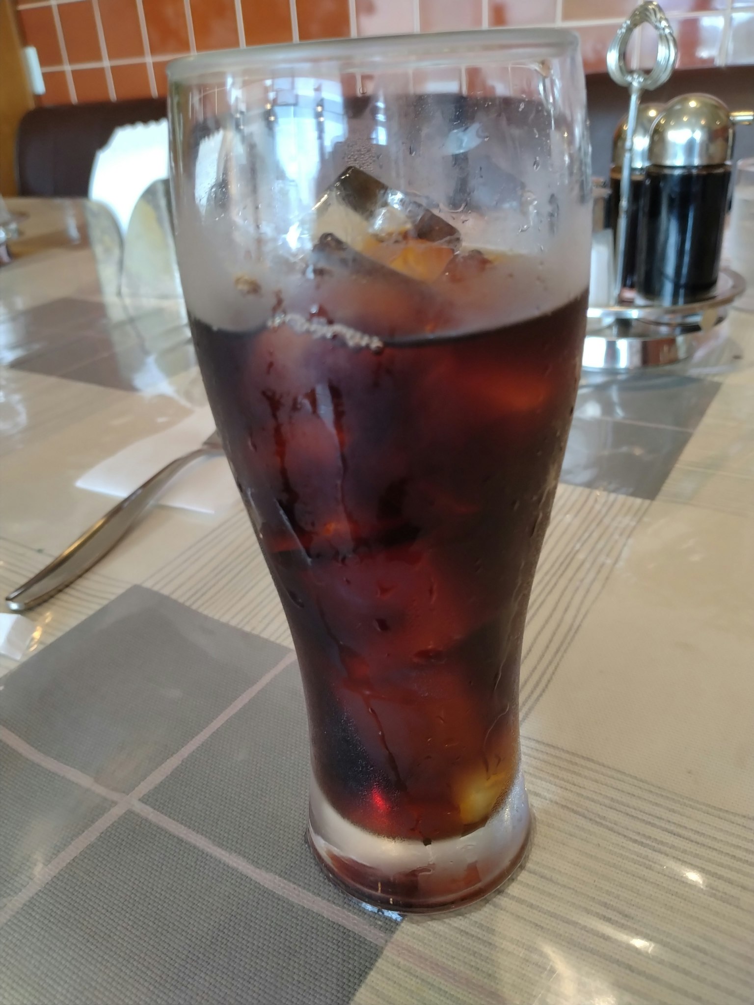 Ein Glas Cola mit Eiswürfeln auf einem Tisch
