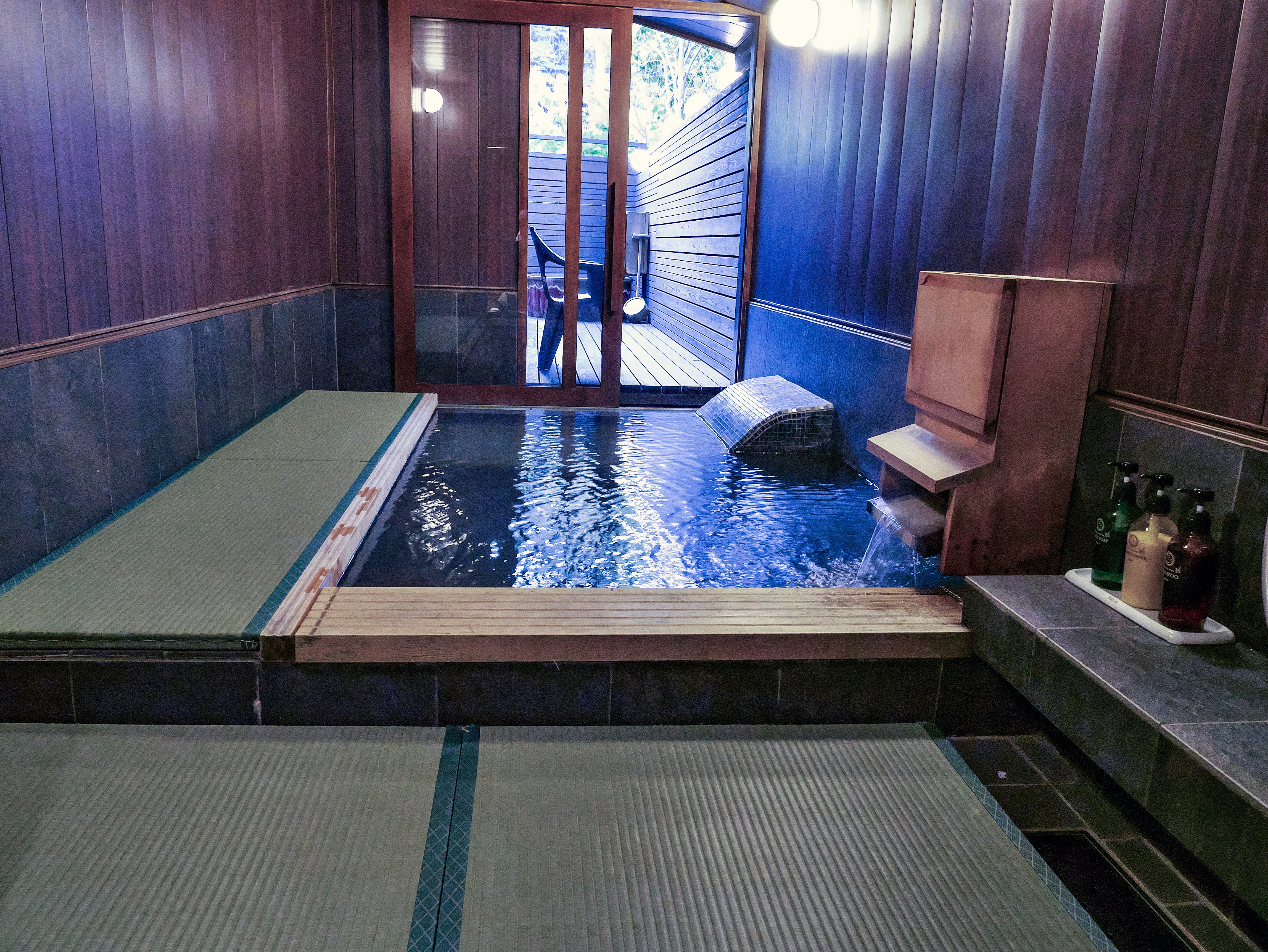 木製の浴室にある小さな温泉風の湯船と畳
