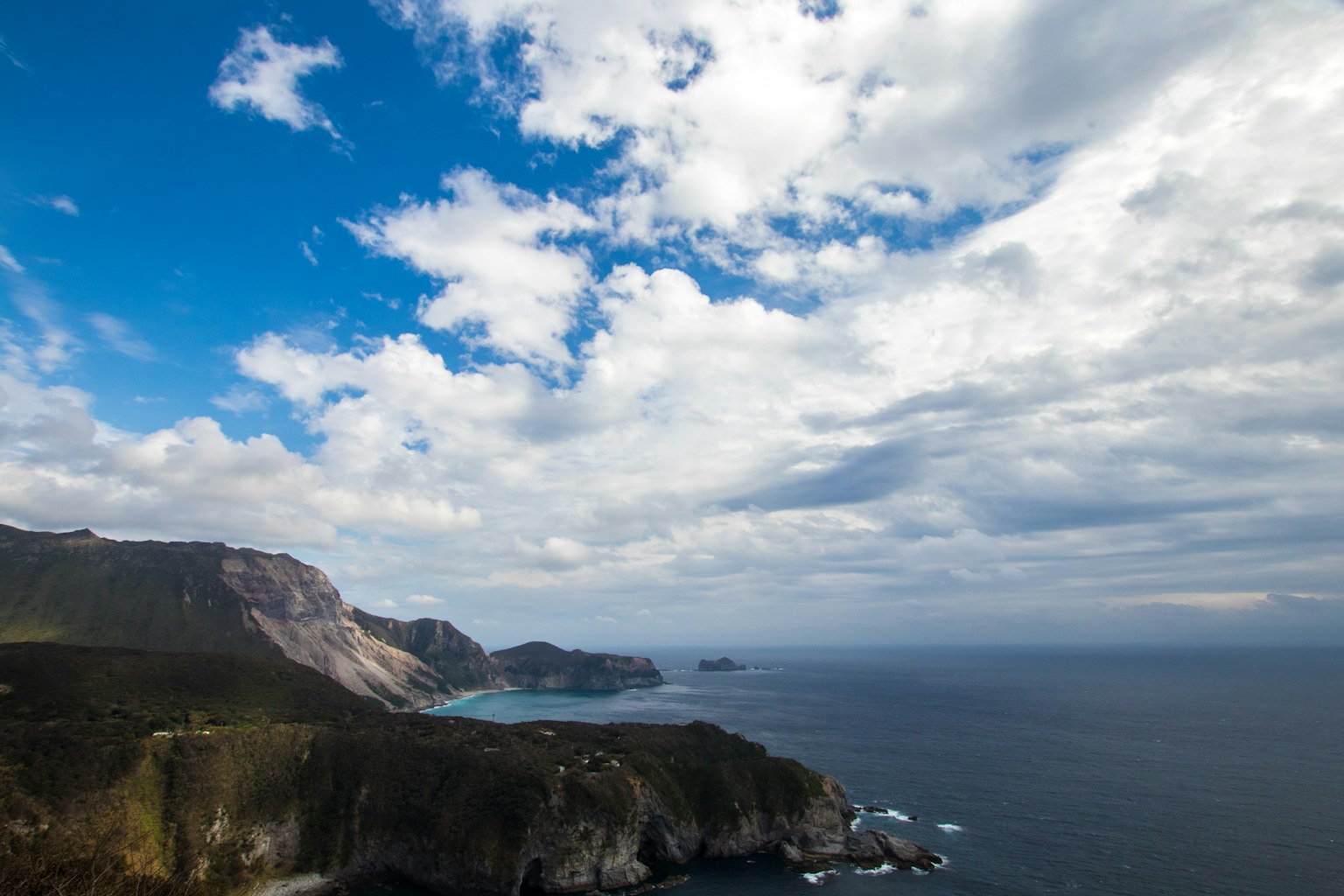 Paesaggio costiero con cielo blu e nuvole montagne e oceano visibili
