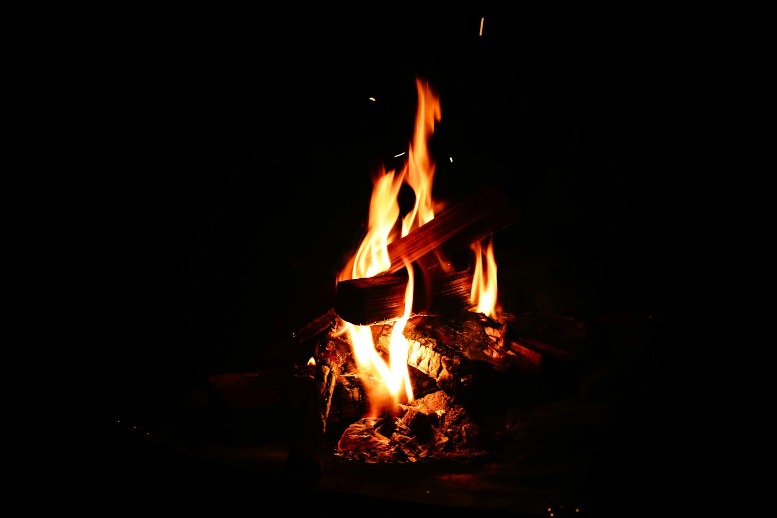 Fiamme di un falò e tronchi che bruciano nel buio