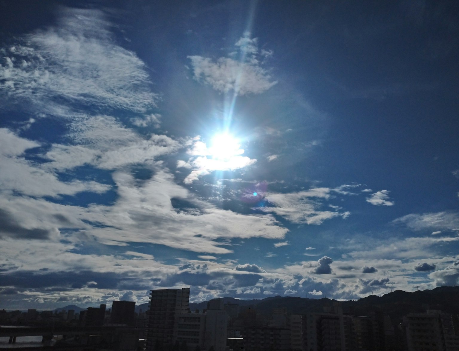Brillante sol brillando a través de nubes blancas en un cielo azul