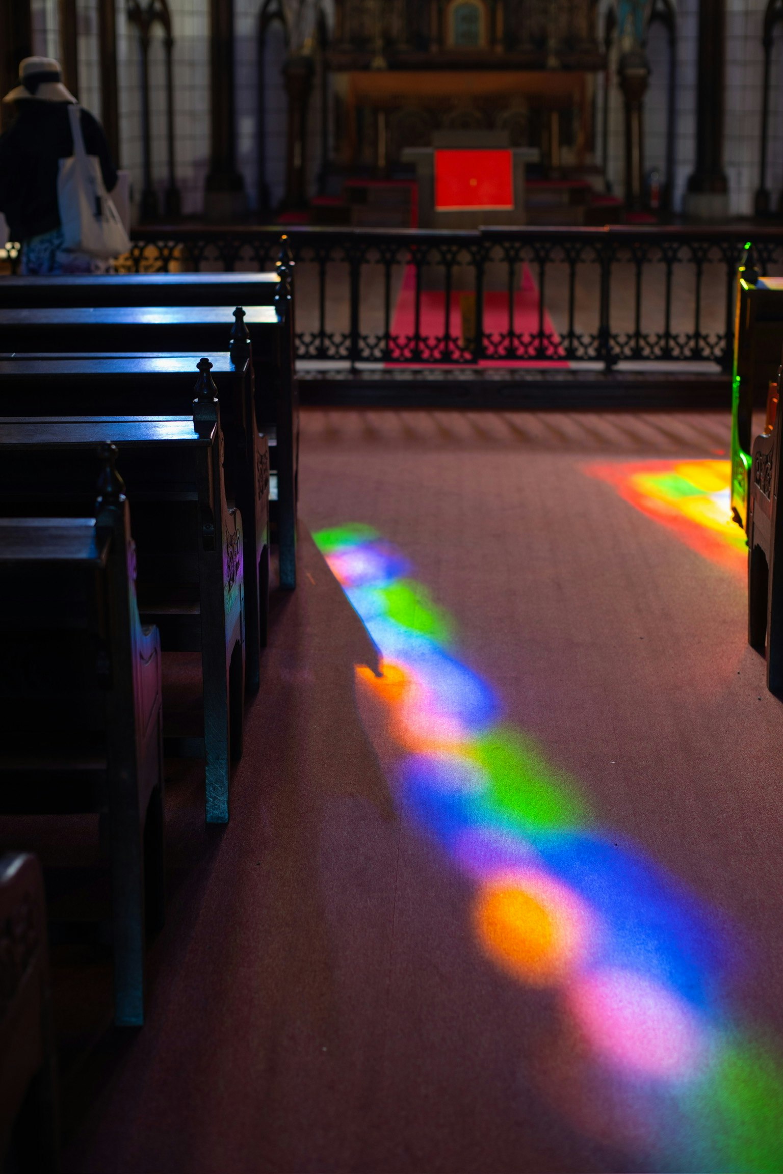 Innenraum einer Kirche mit bunten Lichtmustern auf dem Boden und Bänken