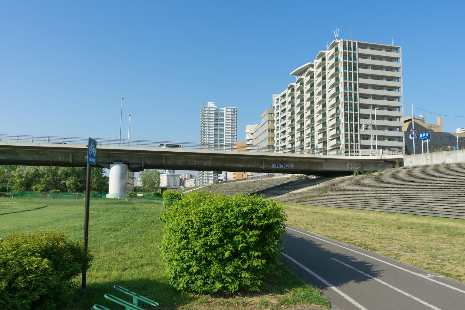 Panorama urbano con grattacieli e un ponte sotto un cielo blu con un parco verde