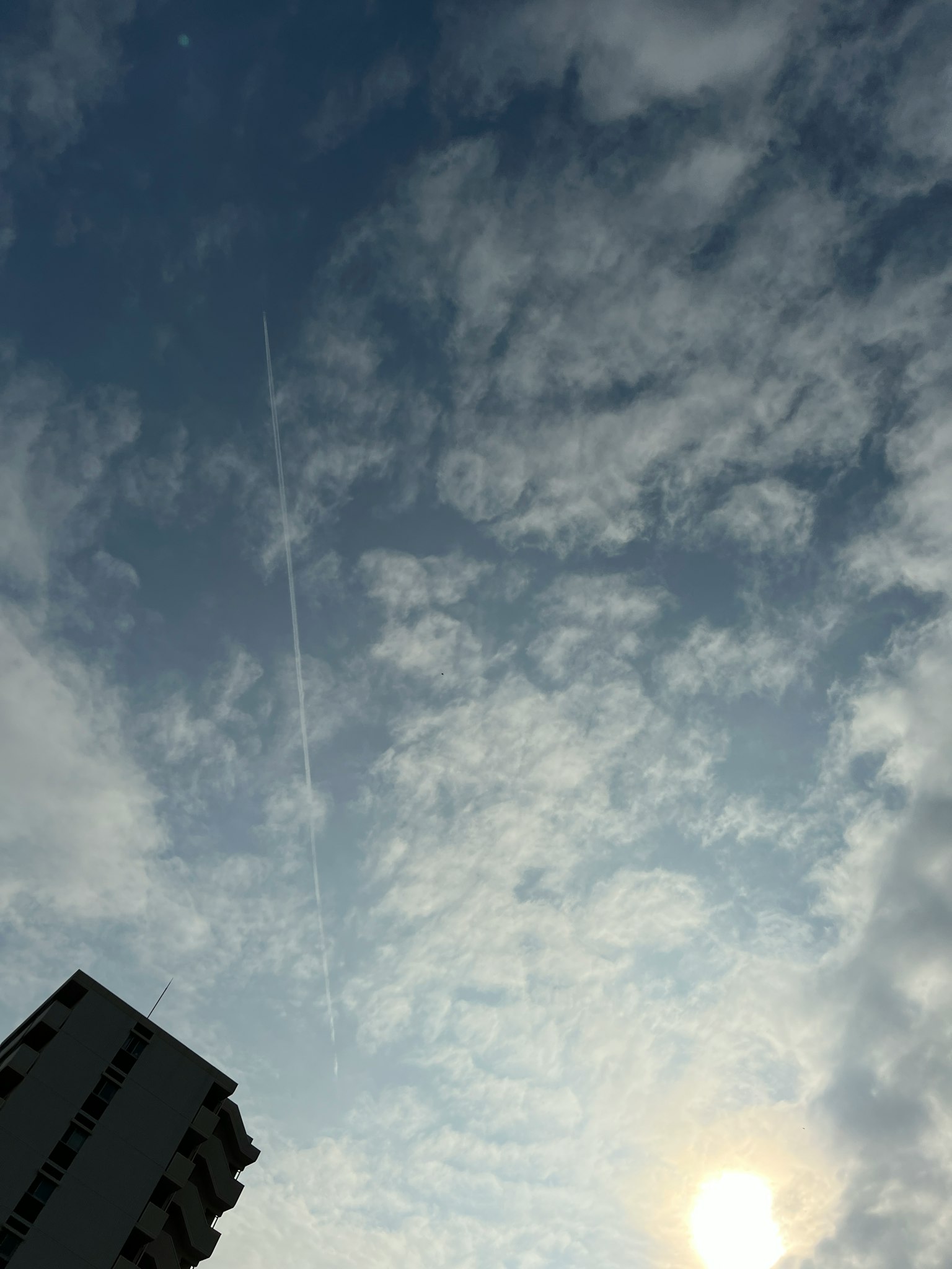 Vista del cielo azul con nubes blancas y la silueta de un edificio