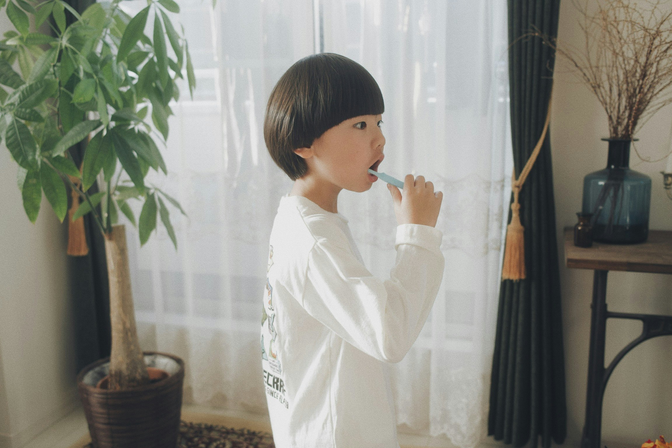 窗邊把手放在嘴邊的女性側臉