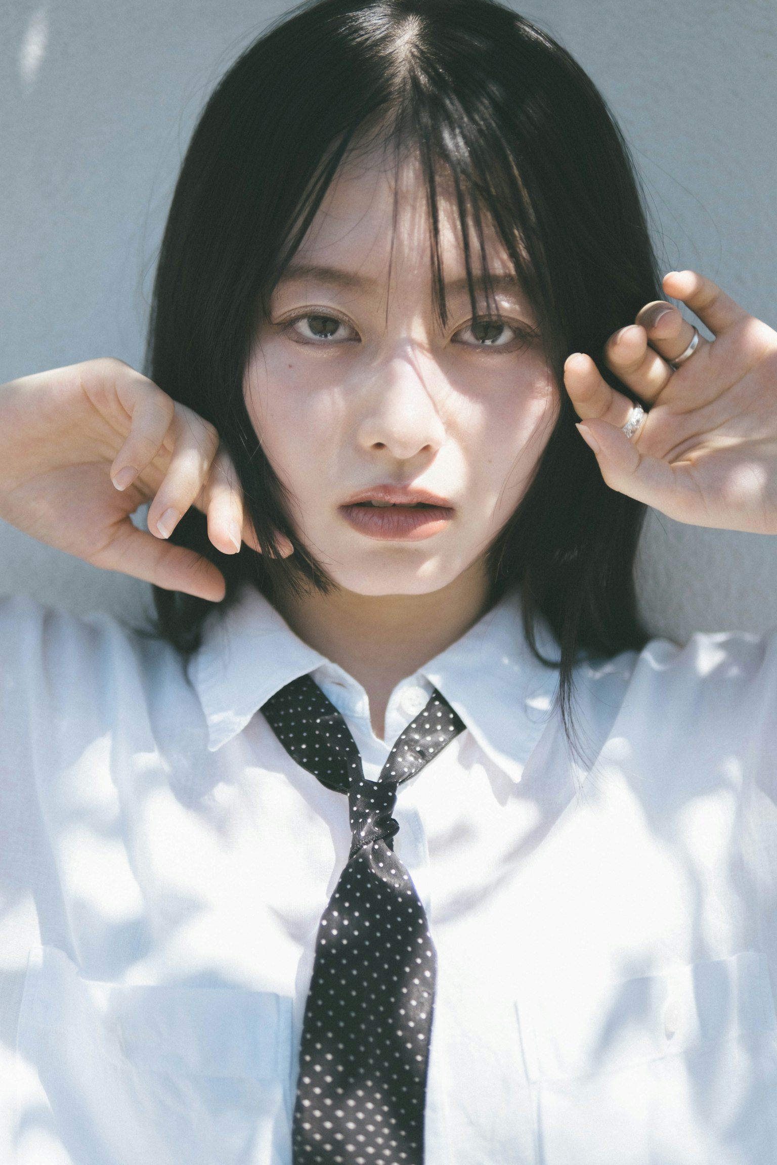 一位年轻女性穿着白色衬衫和领带摆姿势