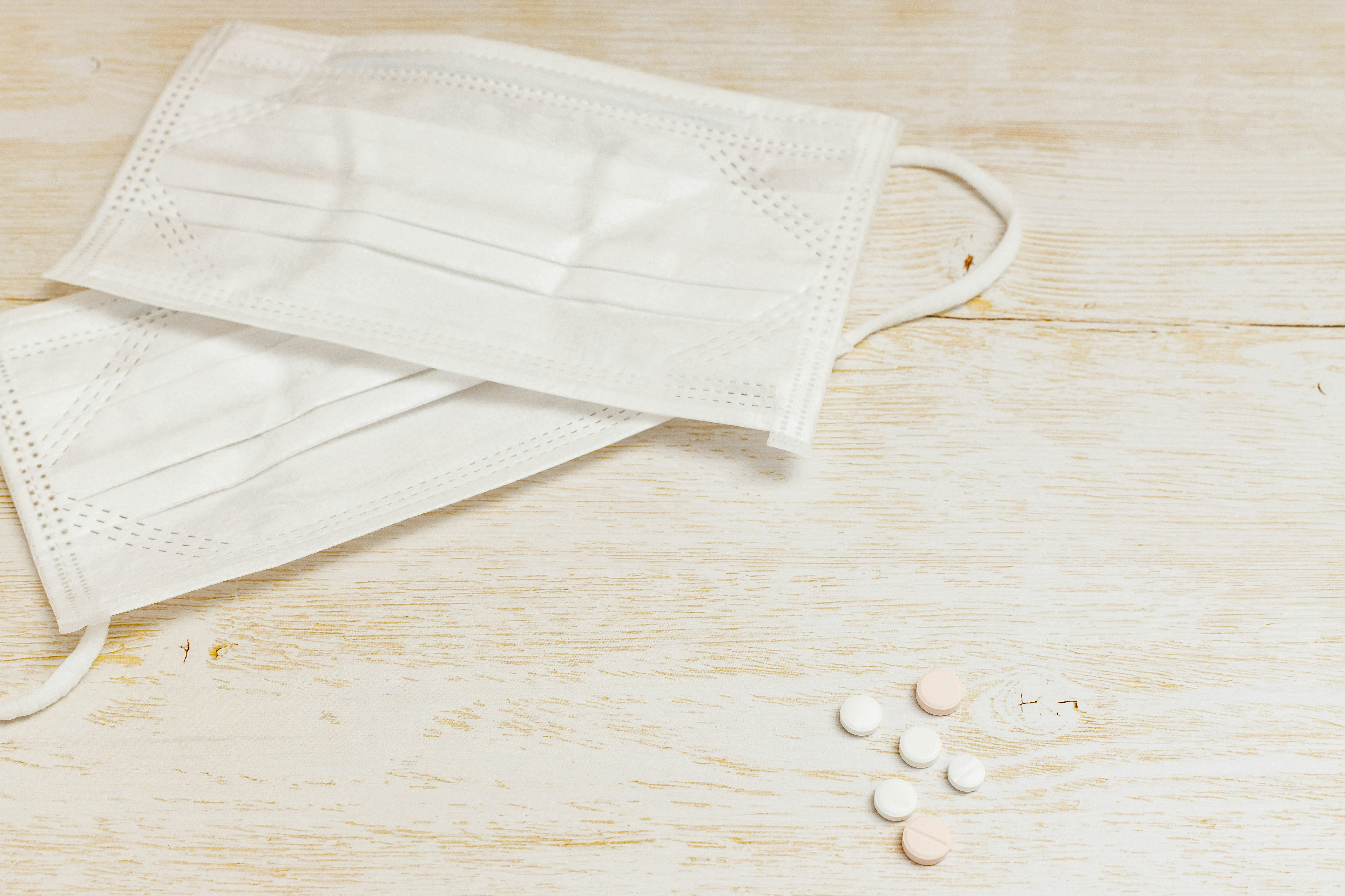 medical face masks and small disinfectant pellets on a wooden surface