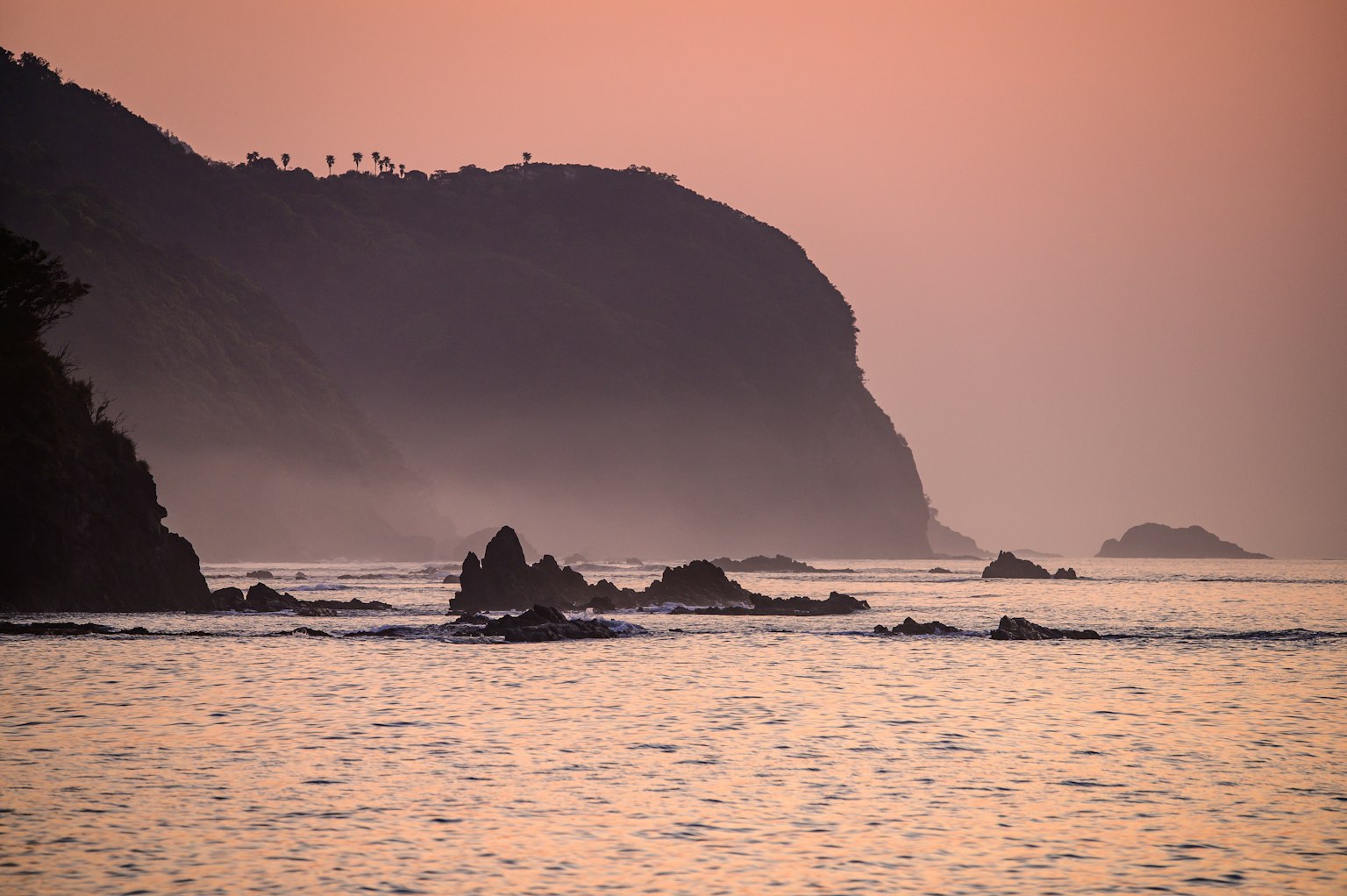 Silhouette de la côte au coucher du soleil avec des formations rocheuses