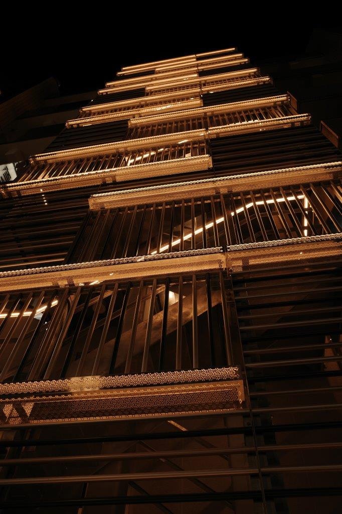 façade d’un grand immeuble la nuit, fenêtres éclairées et structure en grille