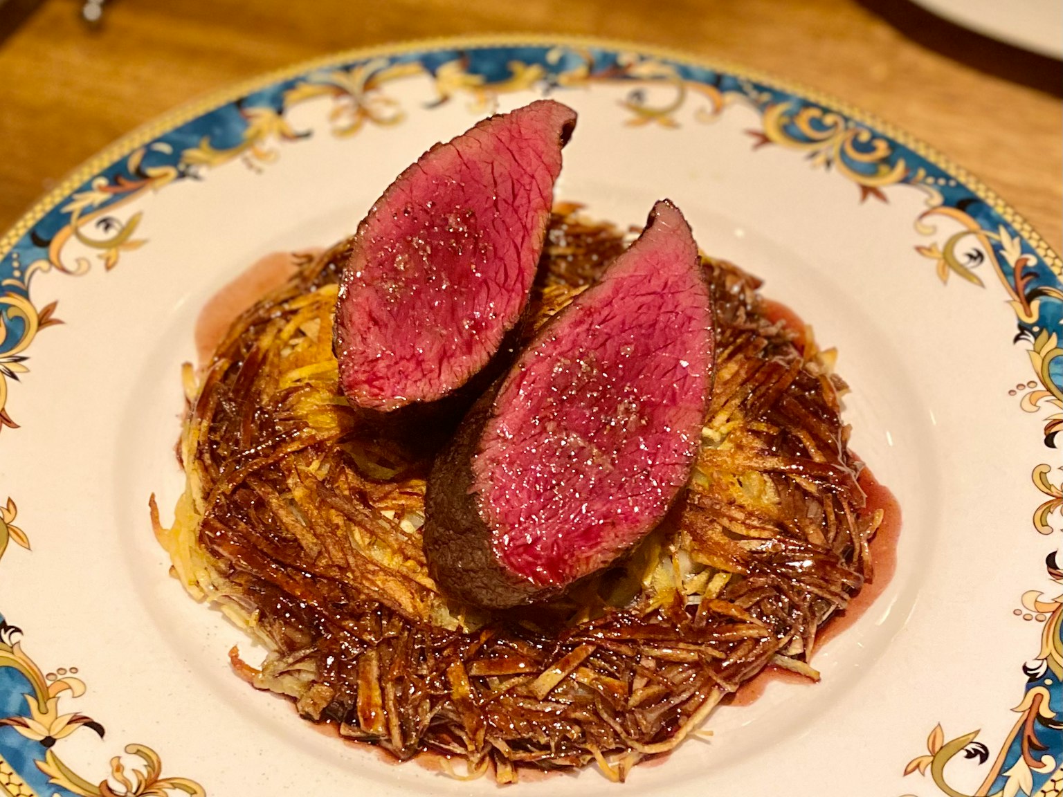 Un plato bellamente presentado con dos rebanadas de carne rosada sobre una base crujiente