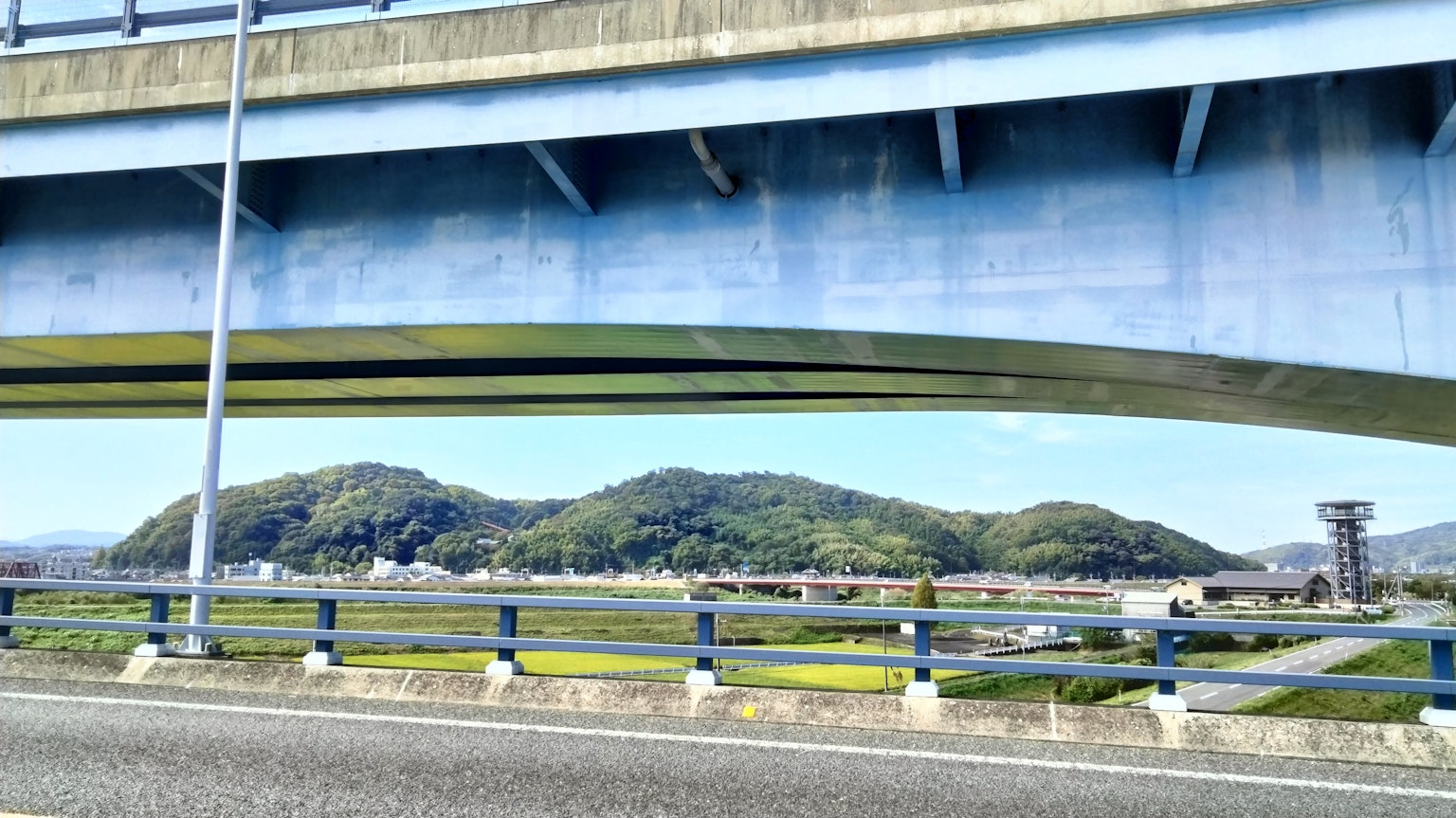 Vue de collines vertes et de paysage rural sous un pont bleu