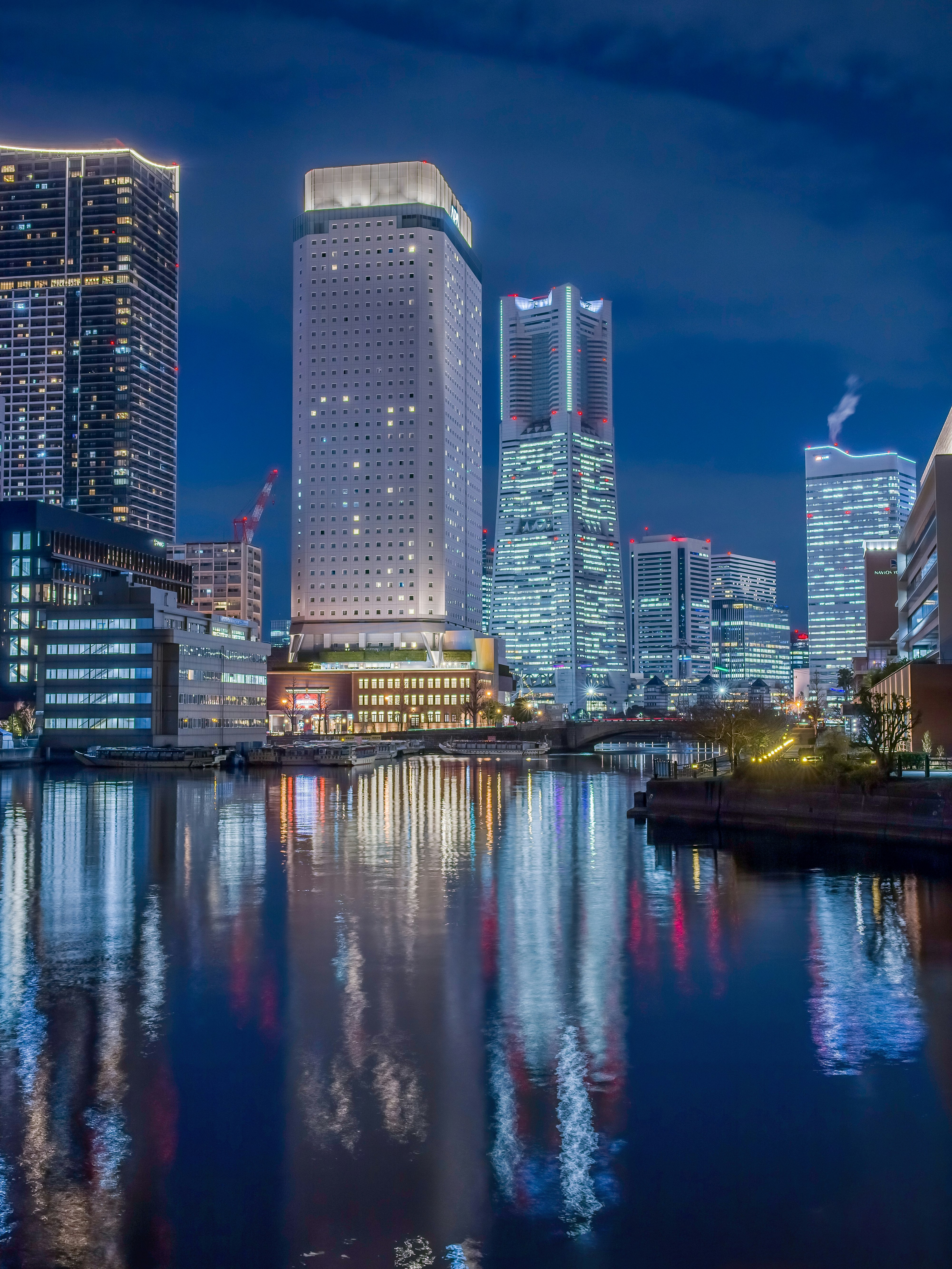 Noche en Yokohama: rascacielos reflejados en el agua del puerto y líneas del puente