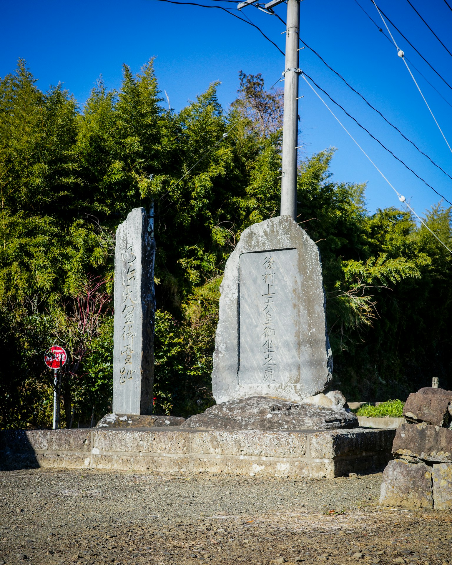 Due grandi monumenti in pietra che si ergono in un paesaggio Circondati da bambù e un palo della luce