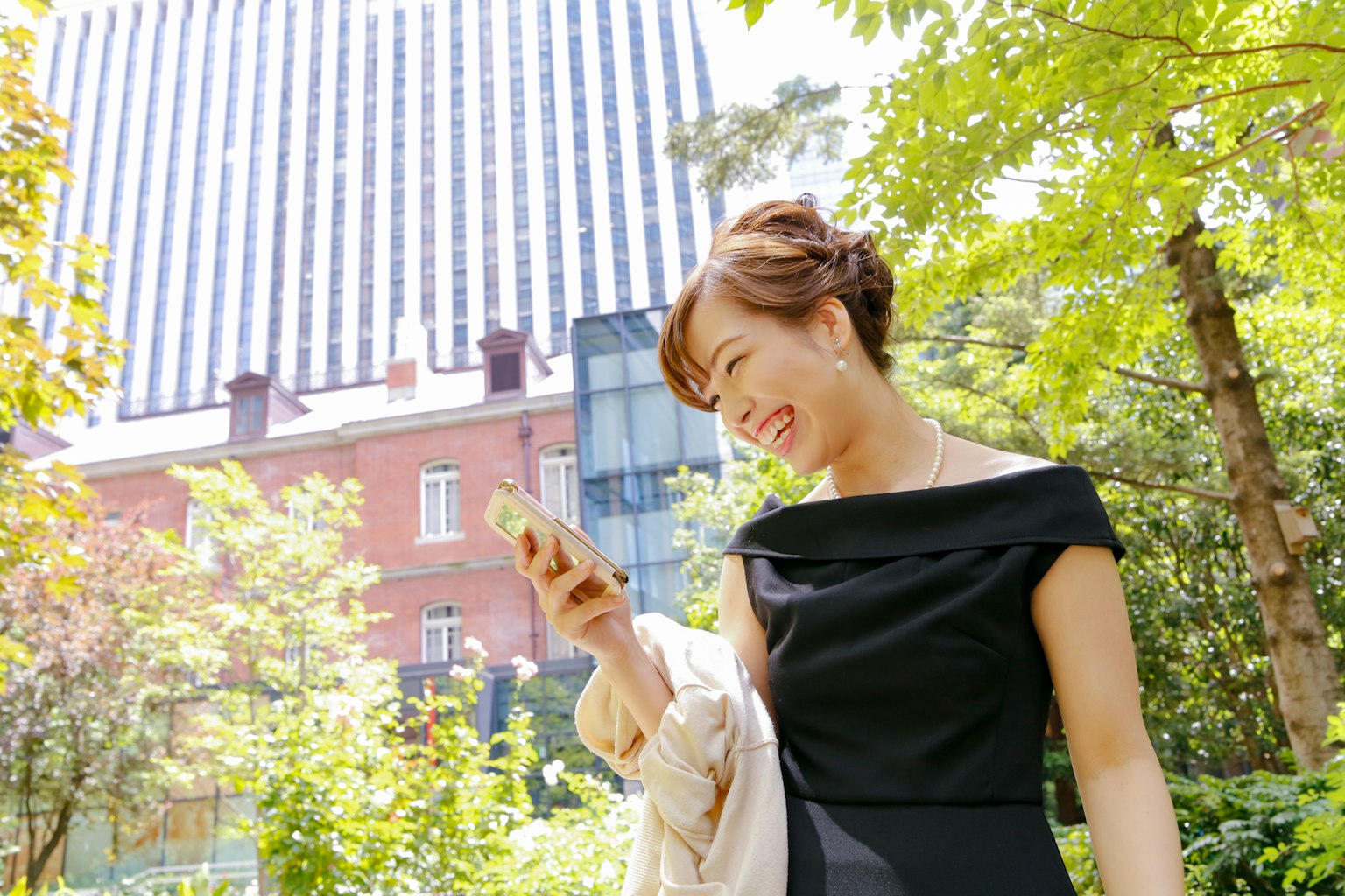Woman smiling while looking at smartphone in a lush green setting