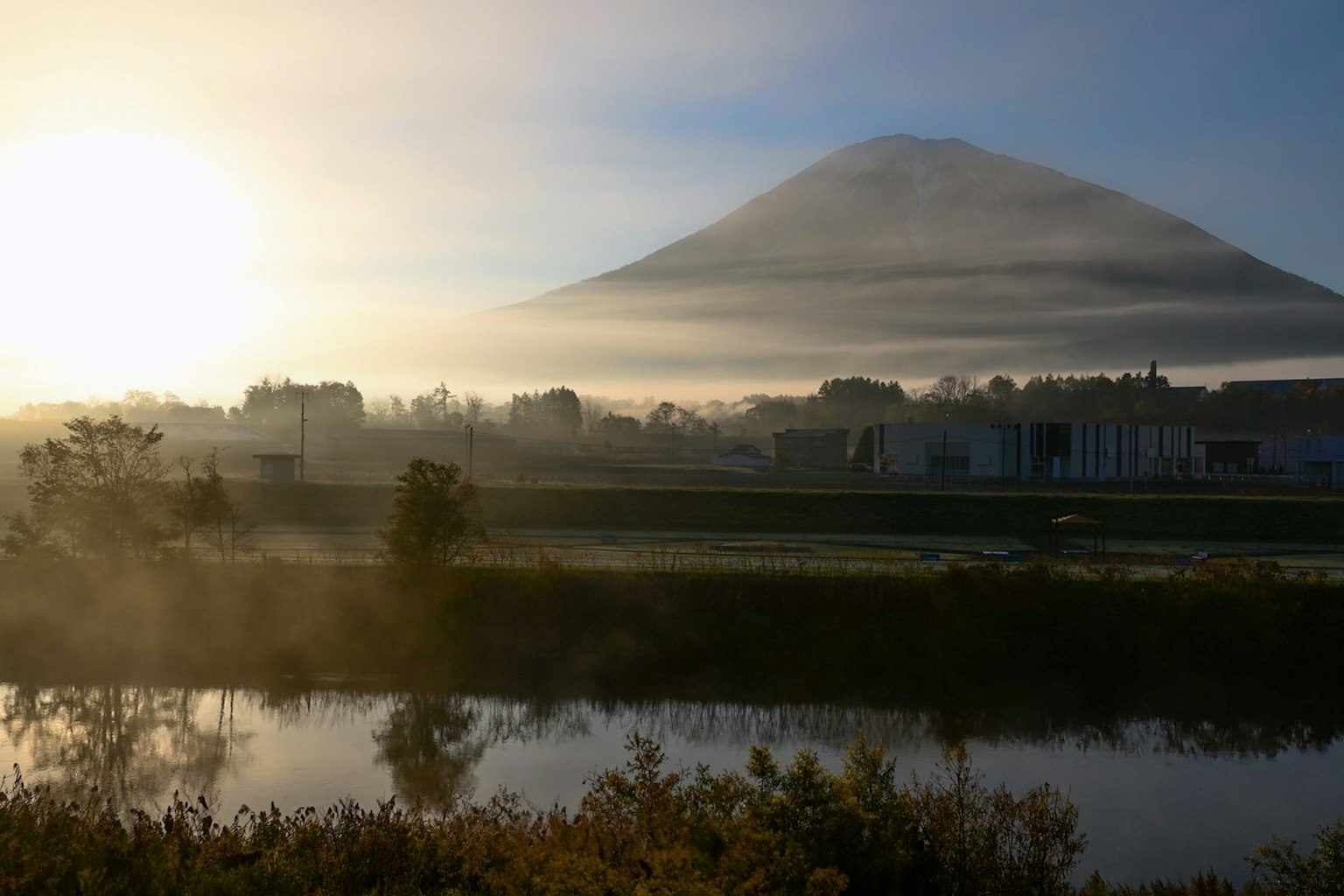 被雾笼罩的富士山与宁静的河流景观