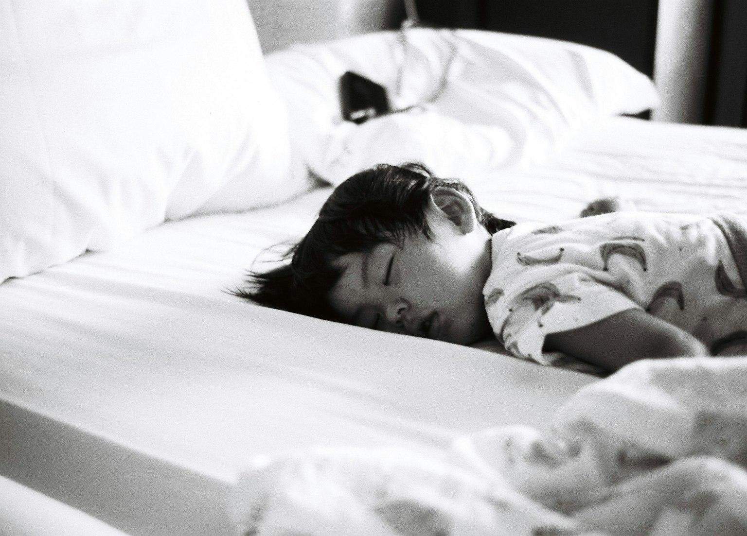 ベッドで寝ている子供のモノクロ写真