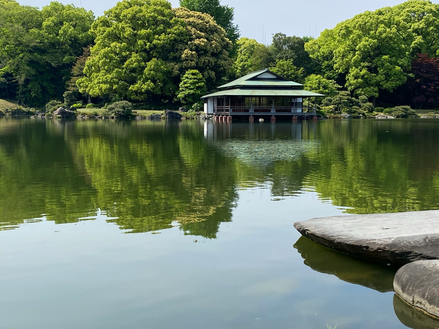 寧靜池塘旁的傳統日本建築，四周環繞著郁郁蔥蔥的樹木