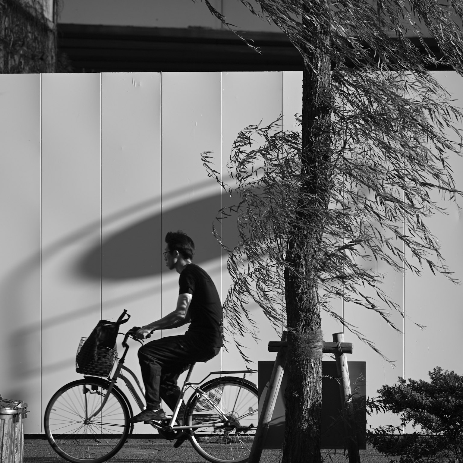 Siluet seorang pria mengendarai sepeda dengan bayangan di dinding putih