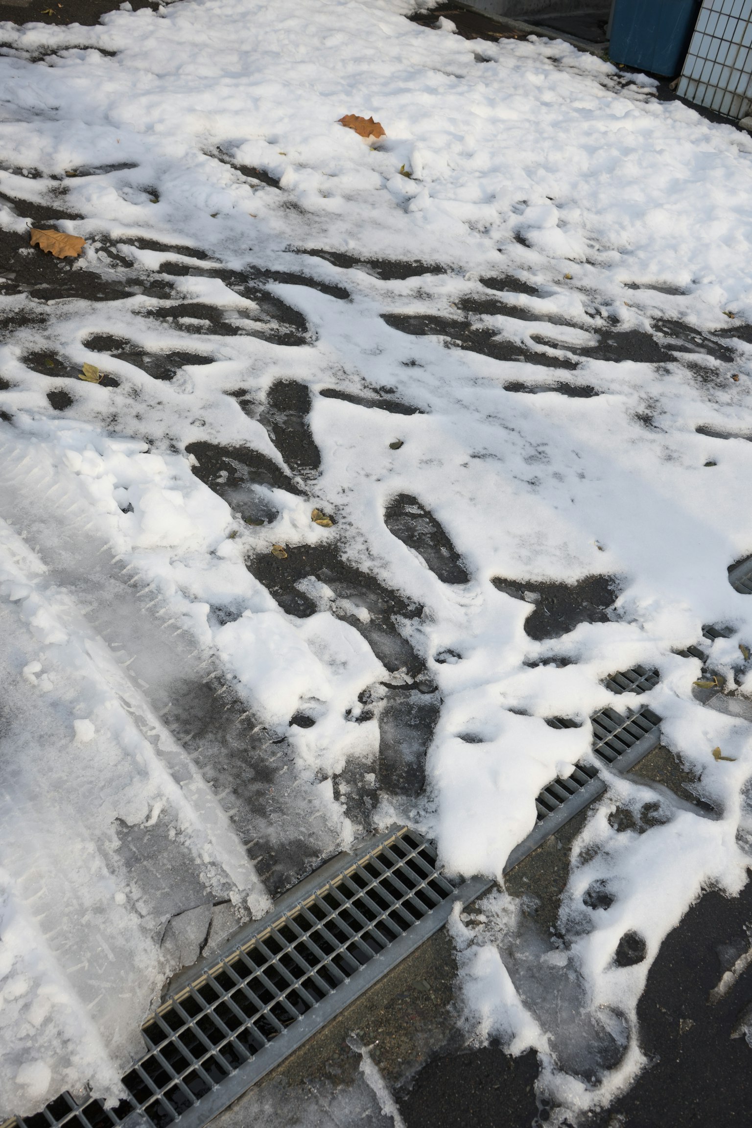 Fußabdrücke auf schneebedecktem Boden mit sichtbarem Abfluss