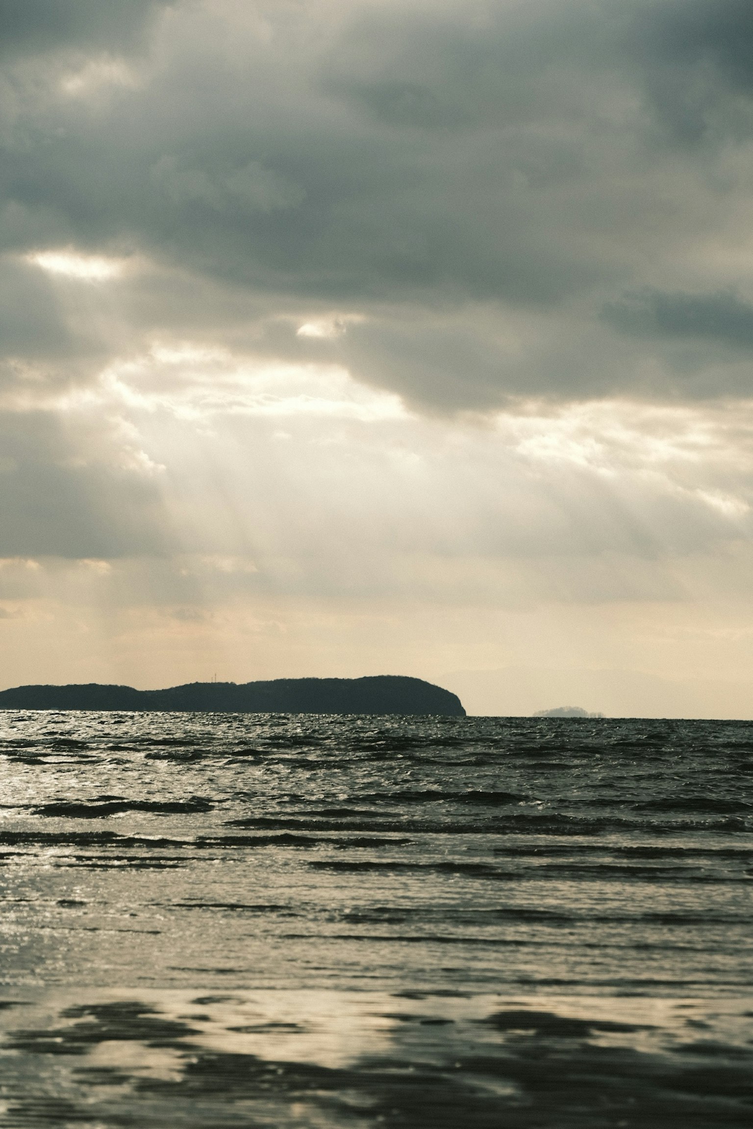 Scena oceanica calma con cielo nuvoloso e isola lontana