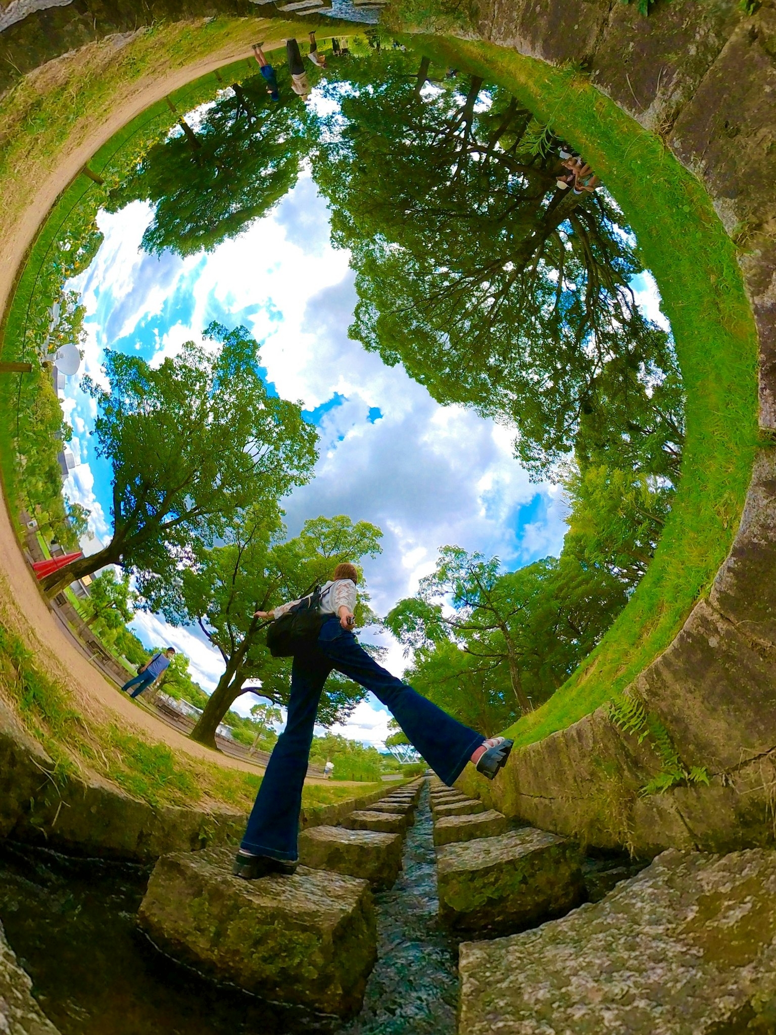 A fisheye lens photo of a person stepping in a lush green park