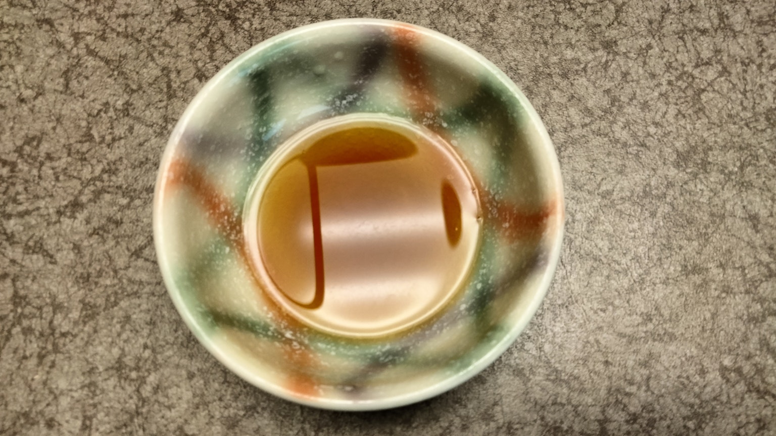 Bild eines braunen Getränks in einer gemusterten Tasse auf einer strukturierten Oberfläche