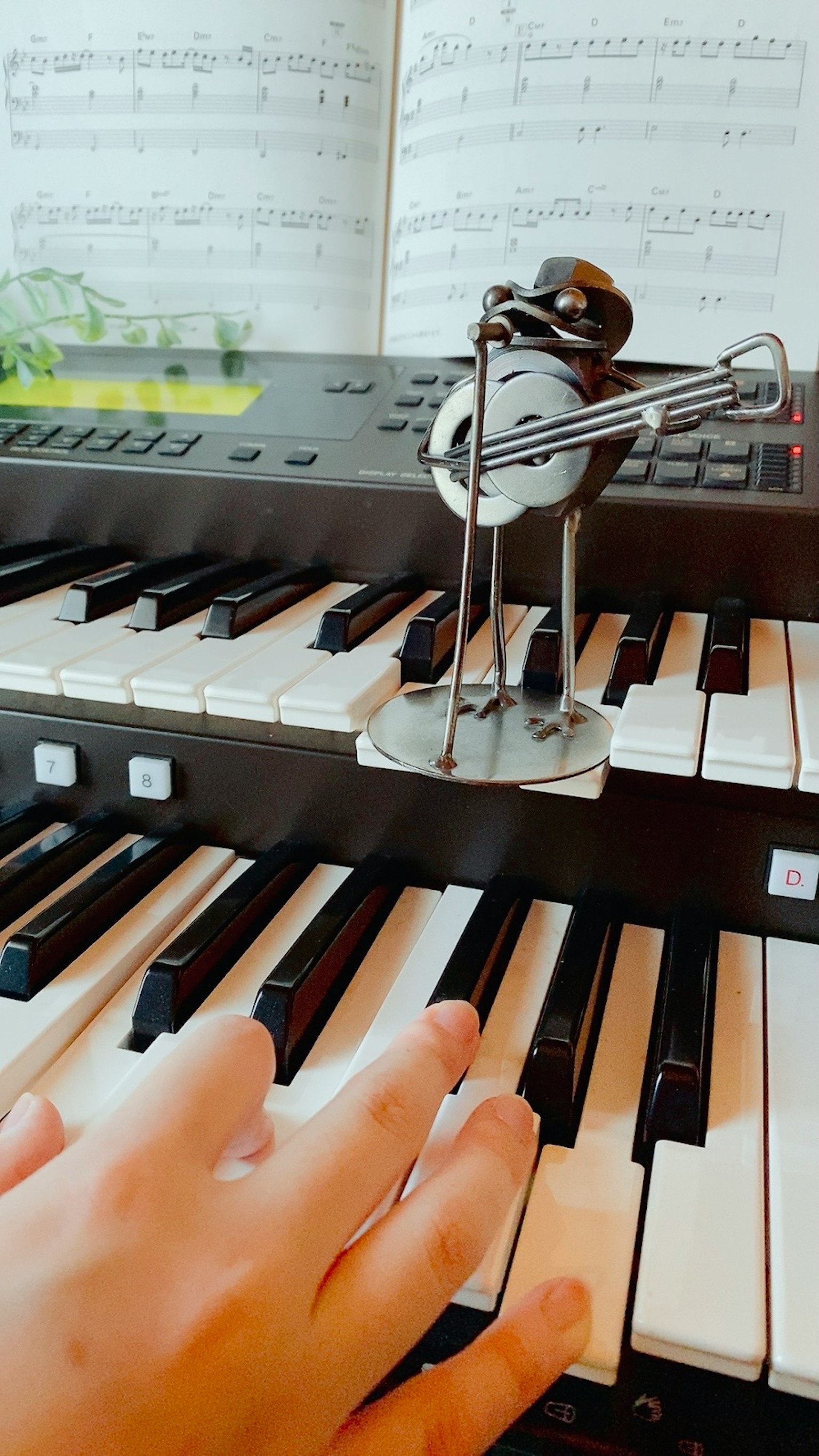Hand playing keyboard with decorative musical figurine