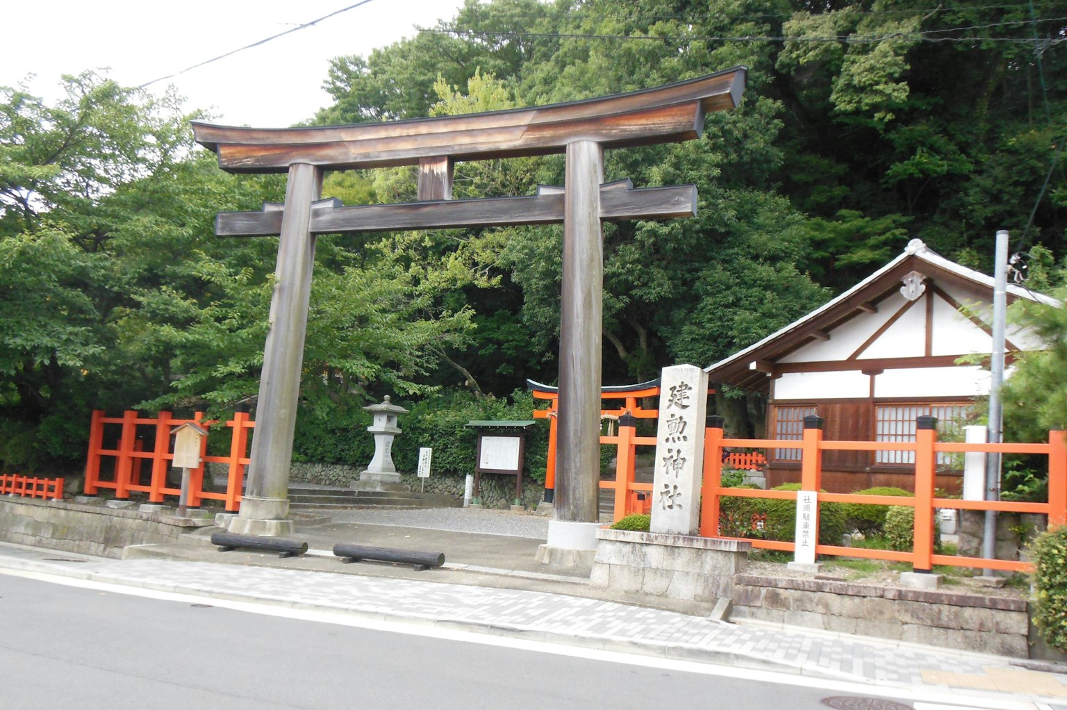 Una vista escénica que presenta un torii rodeado de vegetación y un edificio de santuario tradicional