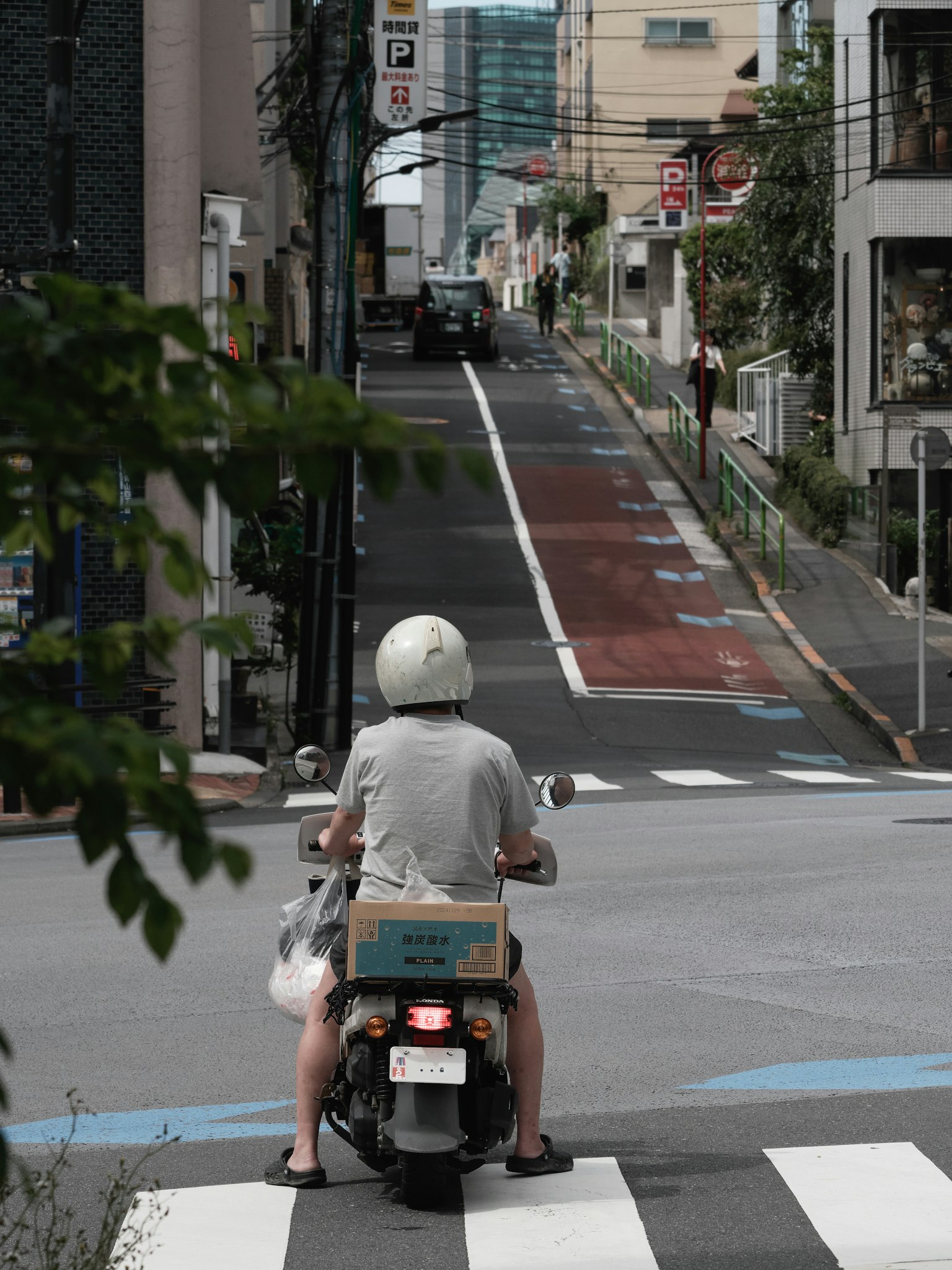 ชายคนหนึ่งขี่สกู๊ตเตอร์ที่สี่แยกพร้อมถนนในเมืองและสัญญาณไฟจราจร