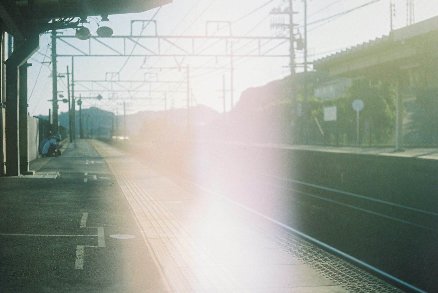 ชานชาลาสถานีรถไฟที่มีแสงแดดและพื้นหลังเบลอ