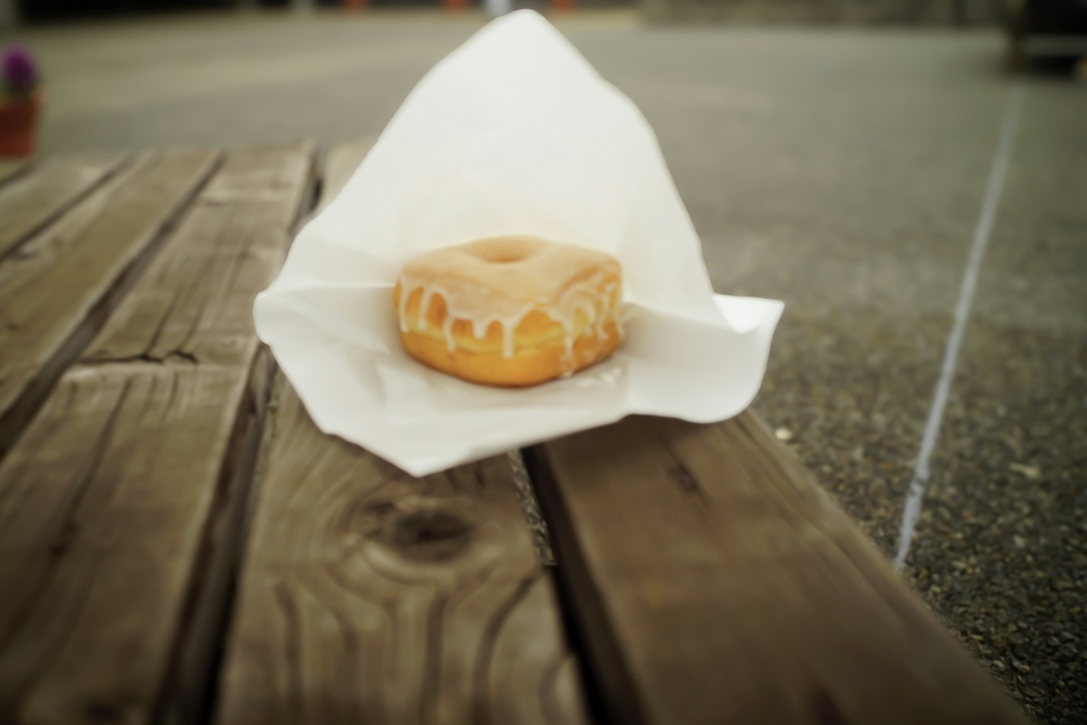 Bánh donut phủ đường trên bàn gỗ được bọc bằng giấy trắng