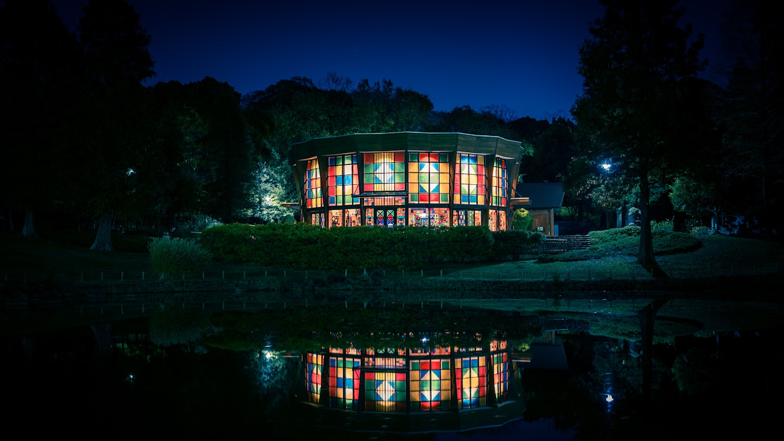 Bellissimo edificio in vetro in un parco che si riflette di notte