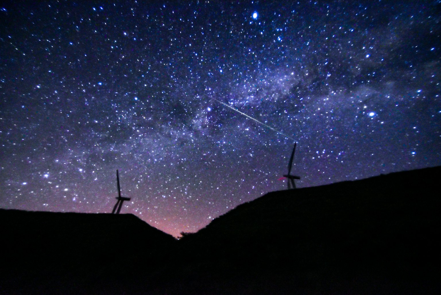 Ciel nocturne magnifique rempli d'étoiles et d'une étoile filante silhouette d'éoliennes