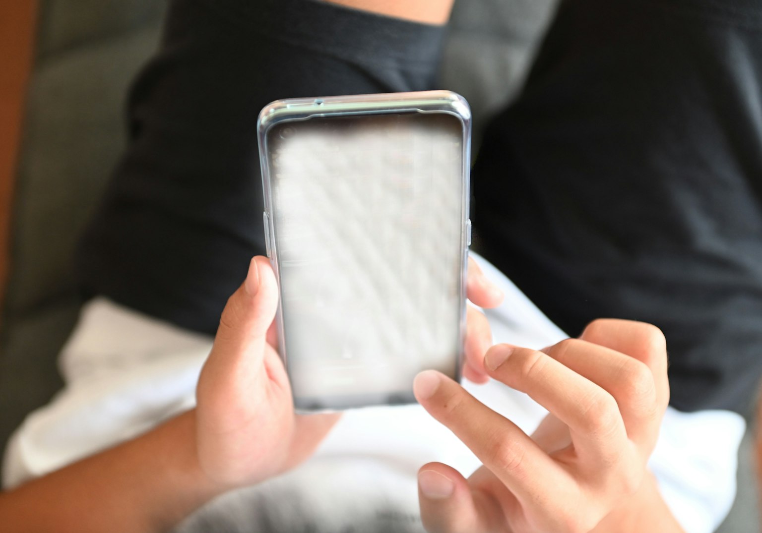 Ein Smartphone in Händen mit einem verschwommenen weißen Bildschirm