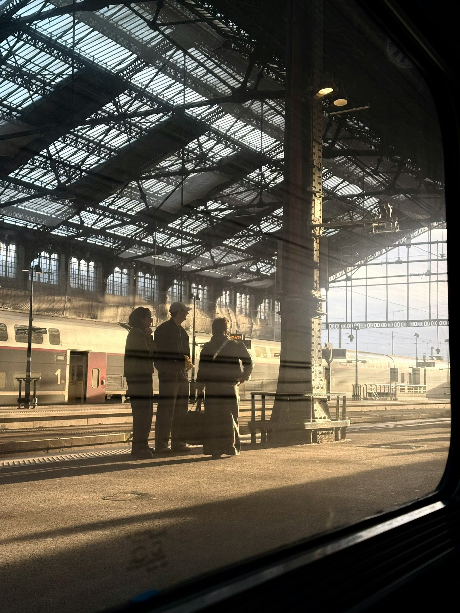 駅のプラットフォームで待つ人々のシルエットと明るい光