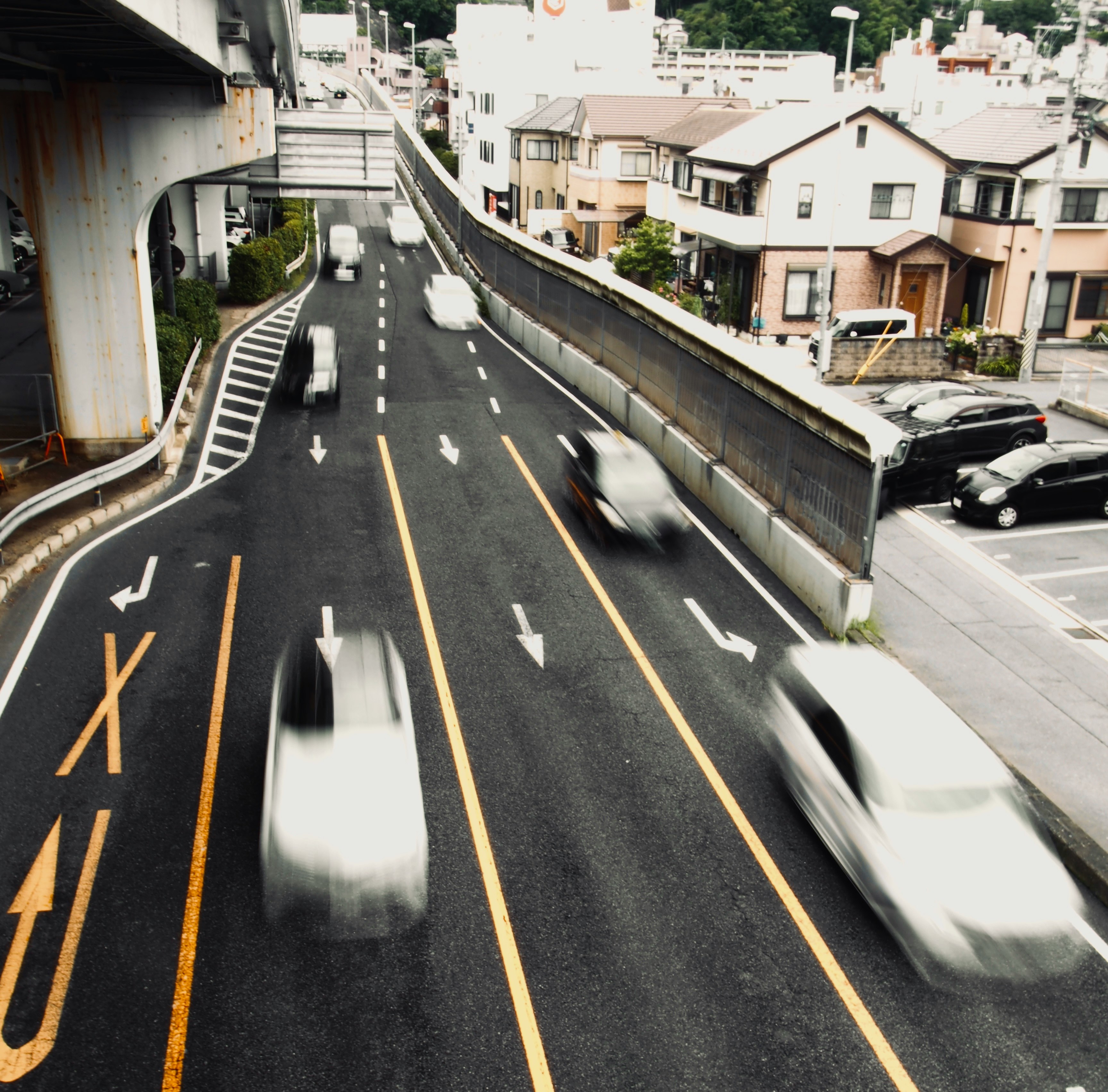 高架下の道路を走る車のある都市の通り